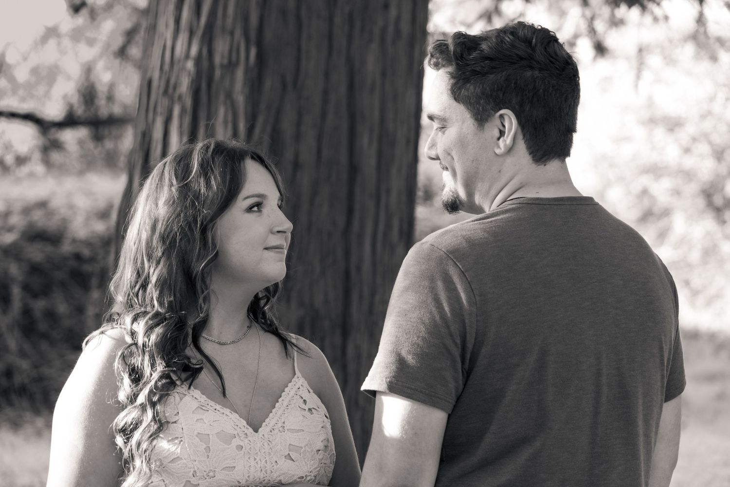 A couple in black and white share intimate moments in a series of romantic outdoor photos by a tree. Yuba City, CA