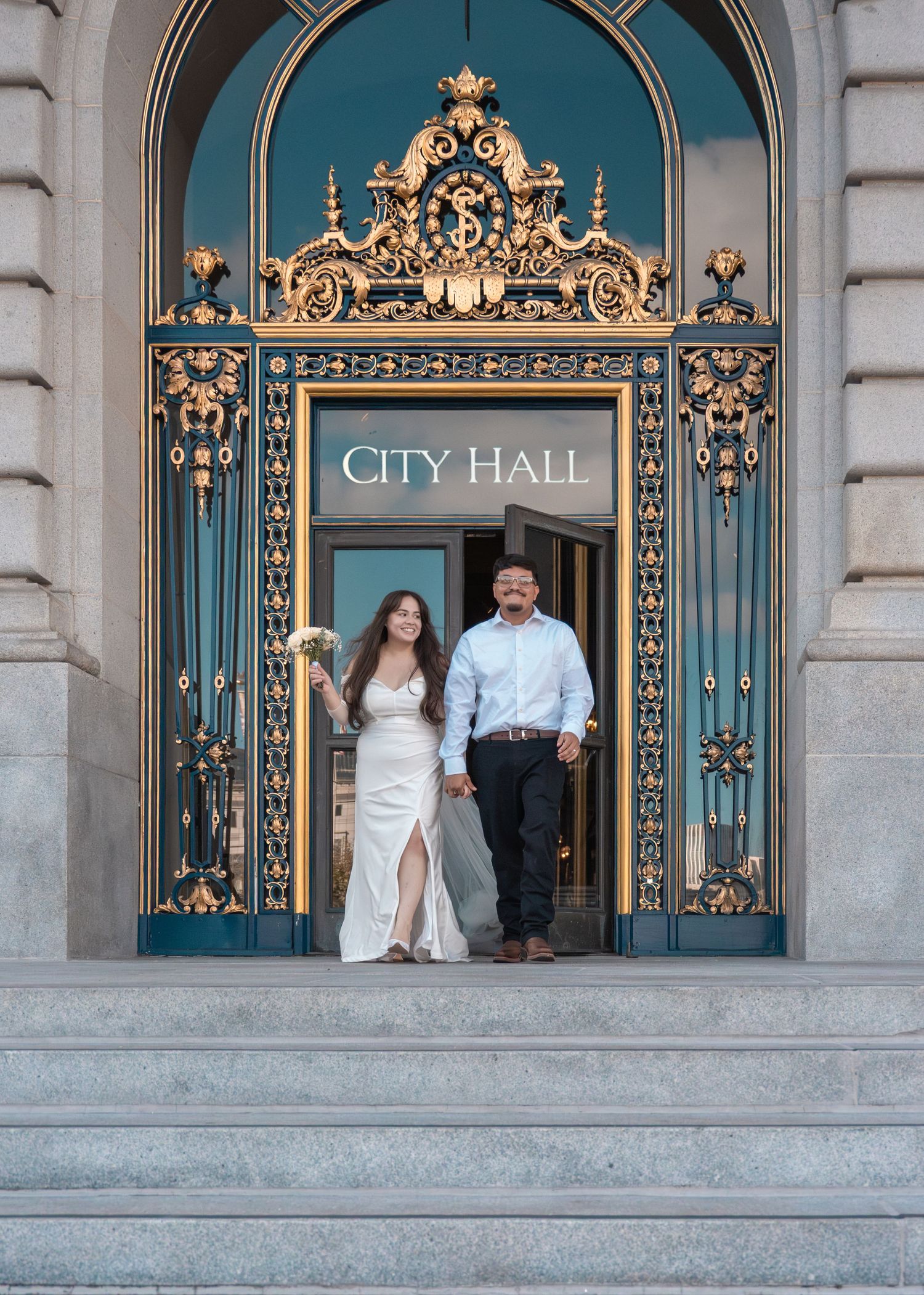 Wedding couple standing at ornate City Hall entrance with blue and gold details.