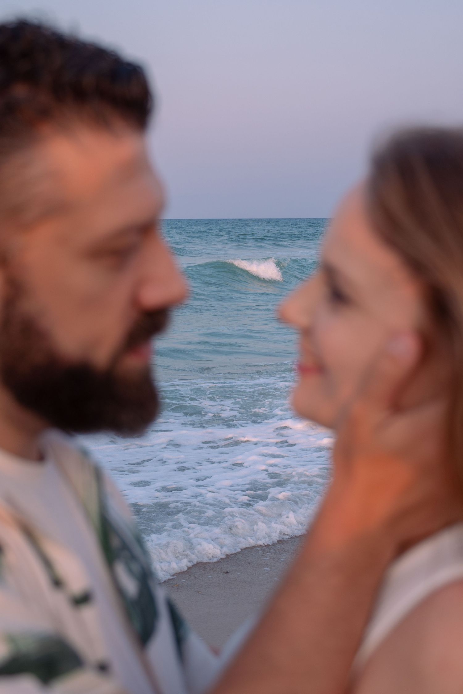 Romantic beach scene at sunset with ocean waves in background.