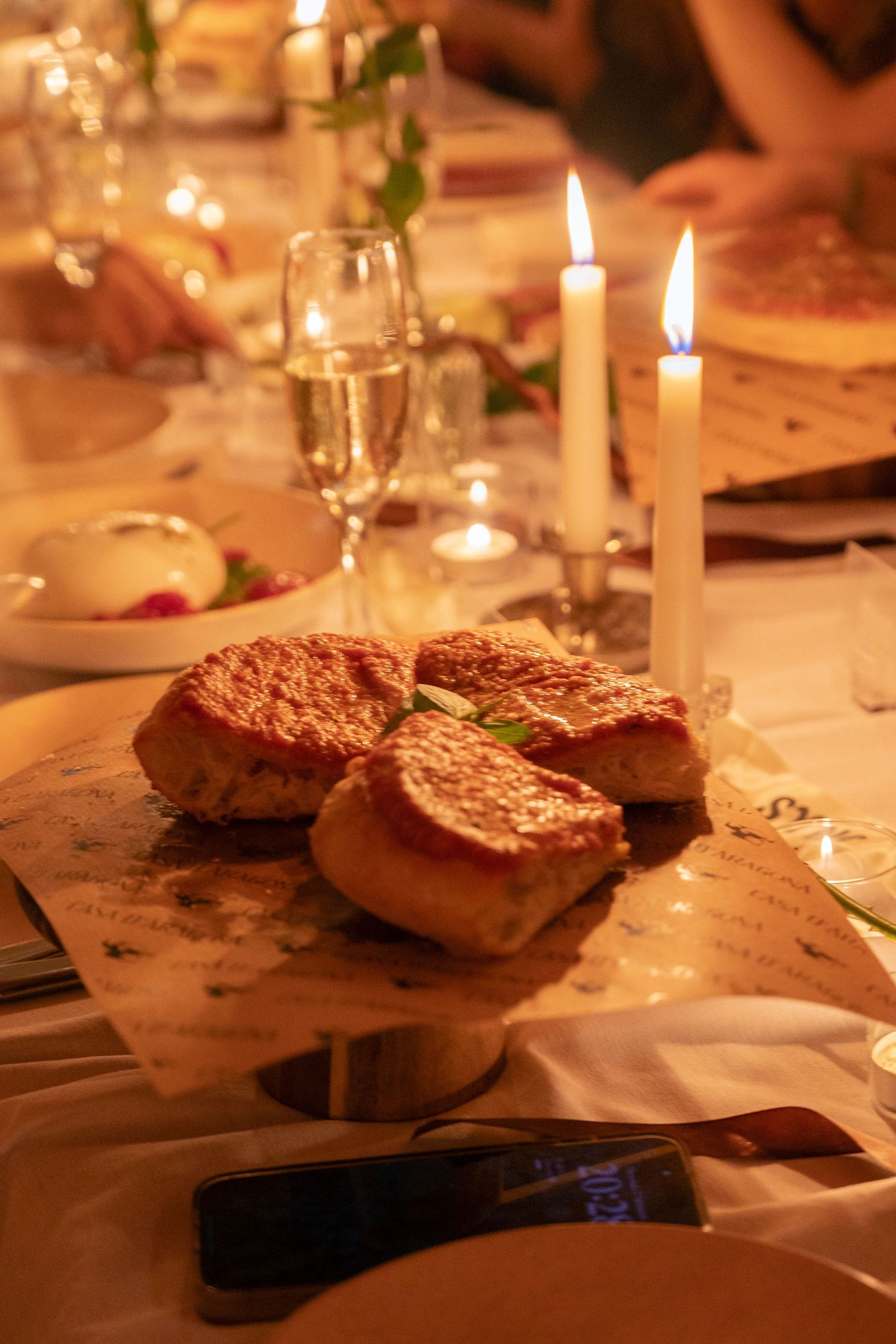 Candlelit dinner table with grilled bread and champagne glasses creating a romantic atmosphere.