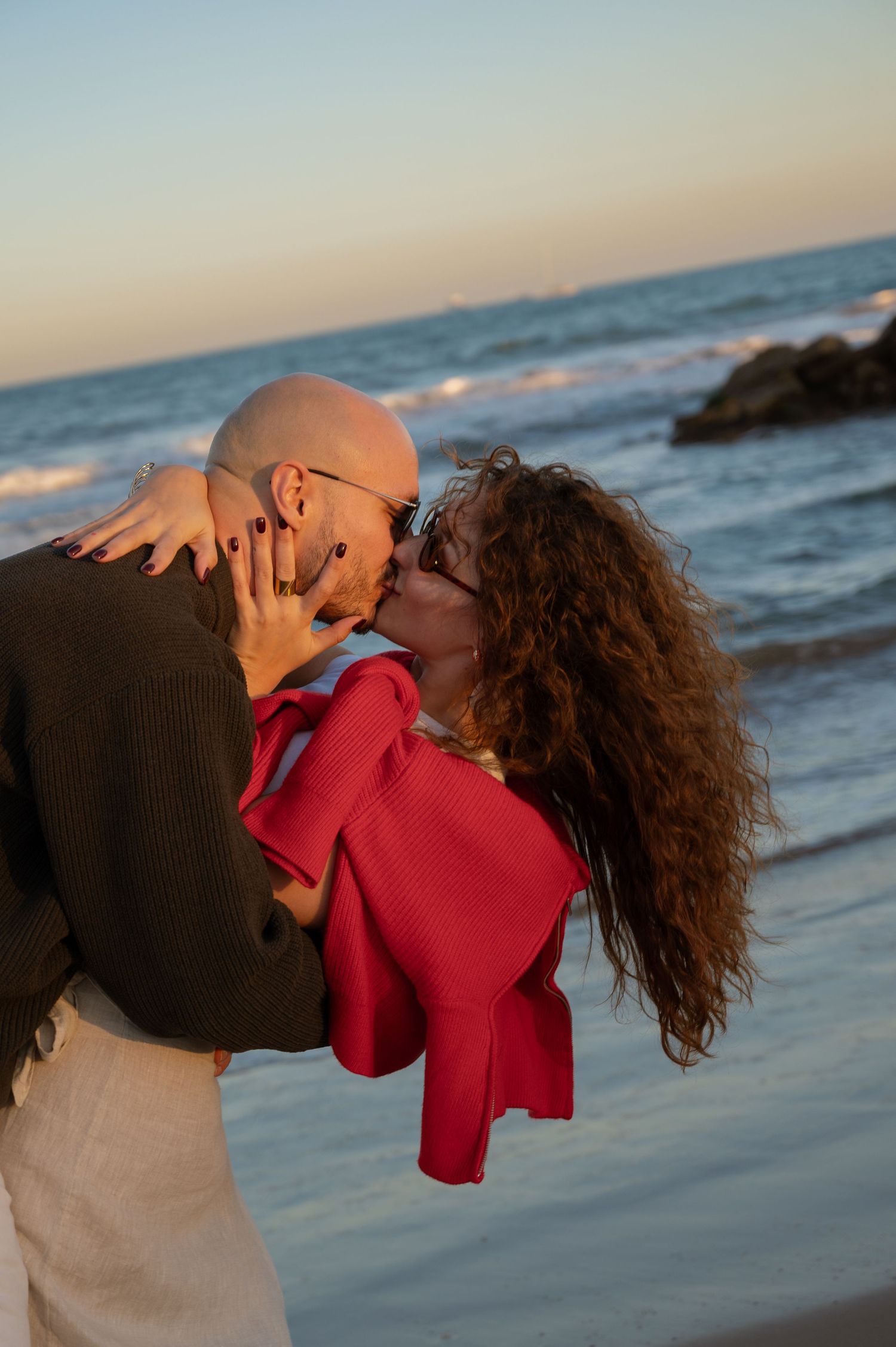 Couple sharing romantic moment on beach at sunset with ocean waves.