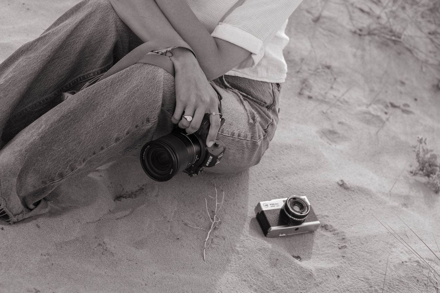 Photographer lying in sand getting creative angle shots at beach location.