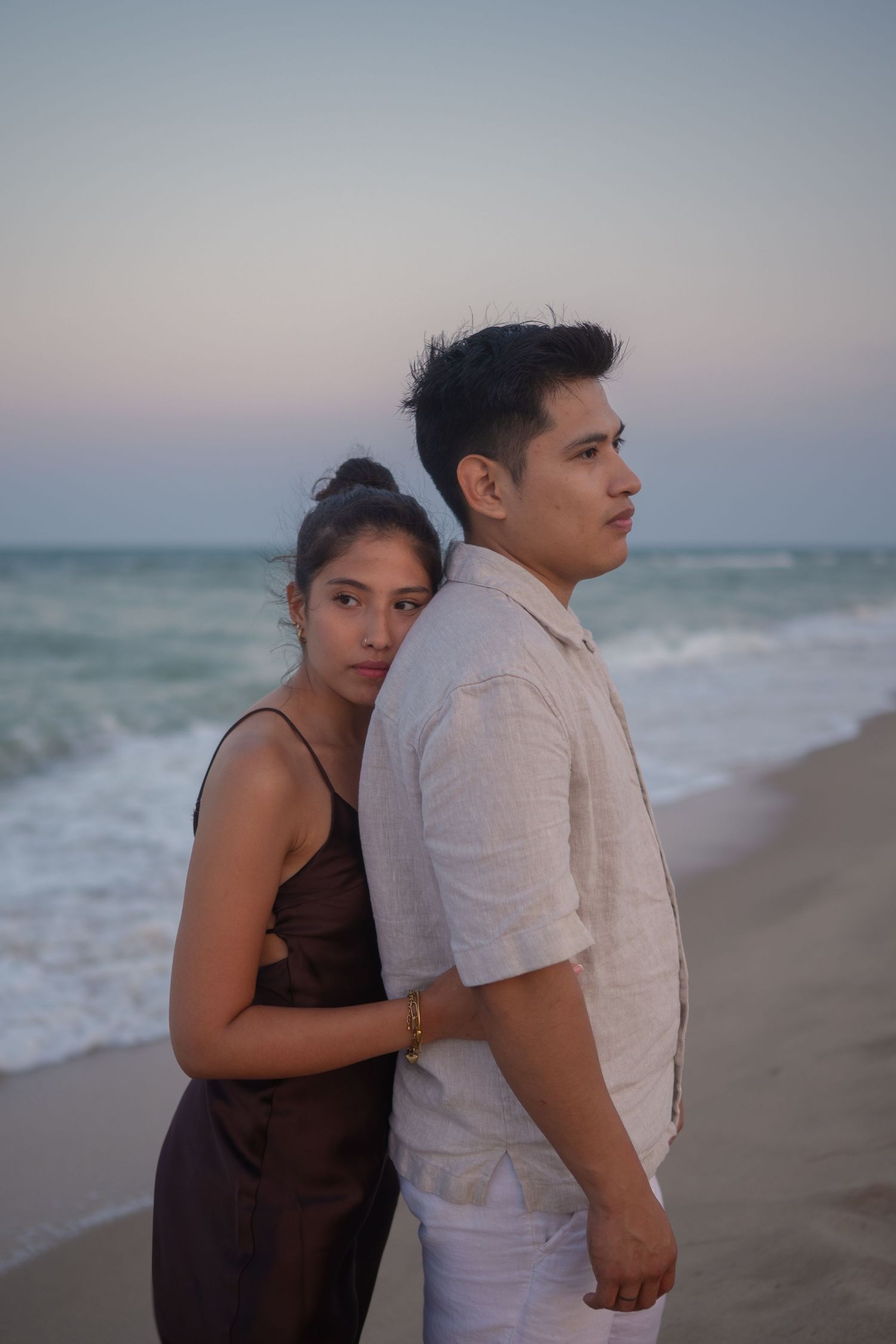 Two people sharing an intimate moment on a beach at sunset.