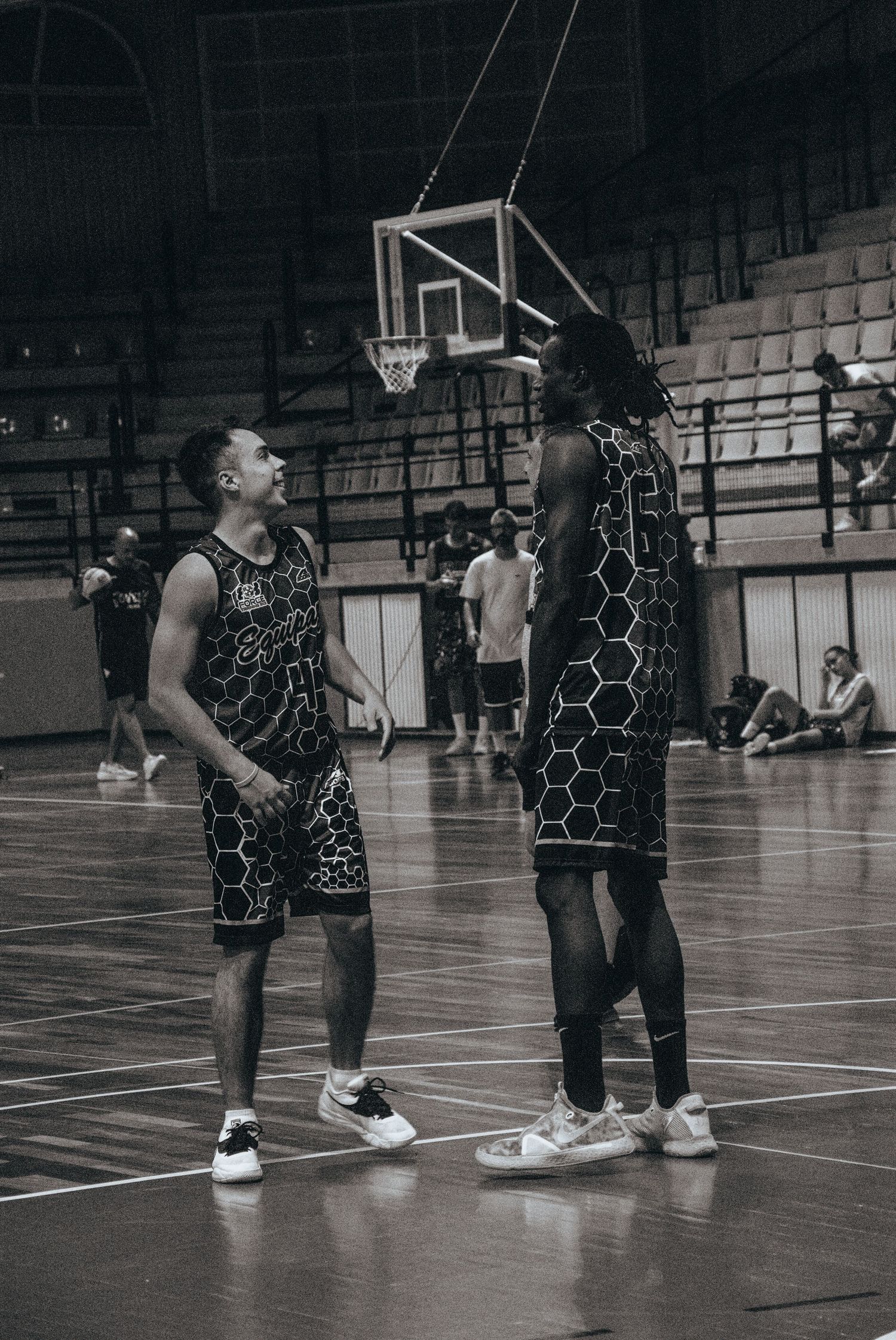 Basketball players in black uniforms practicing defensive moves on an indoor court.