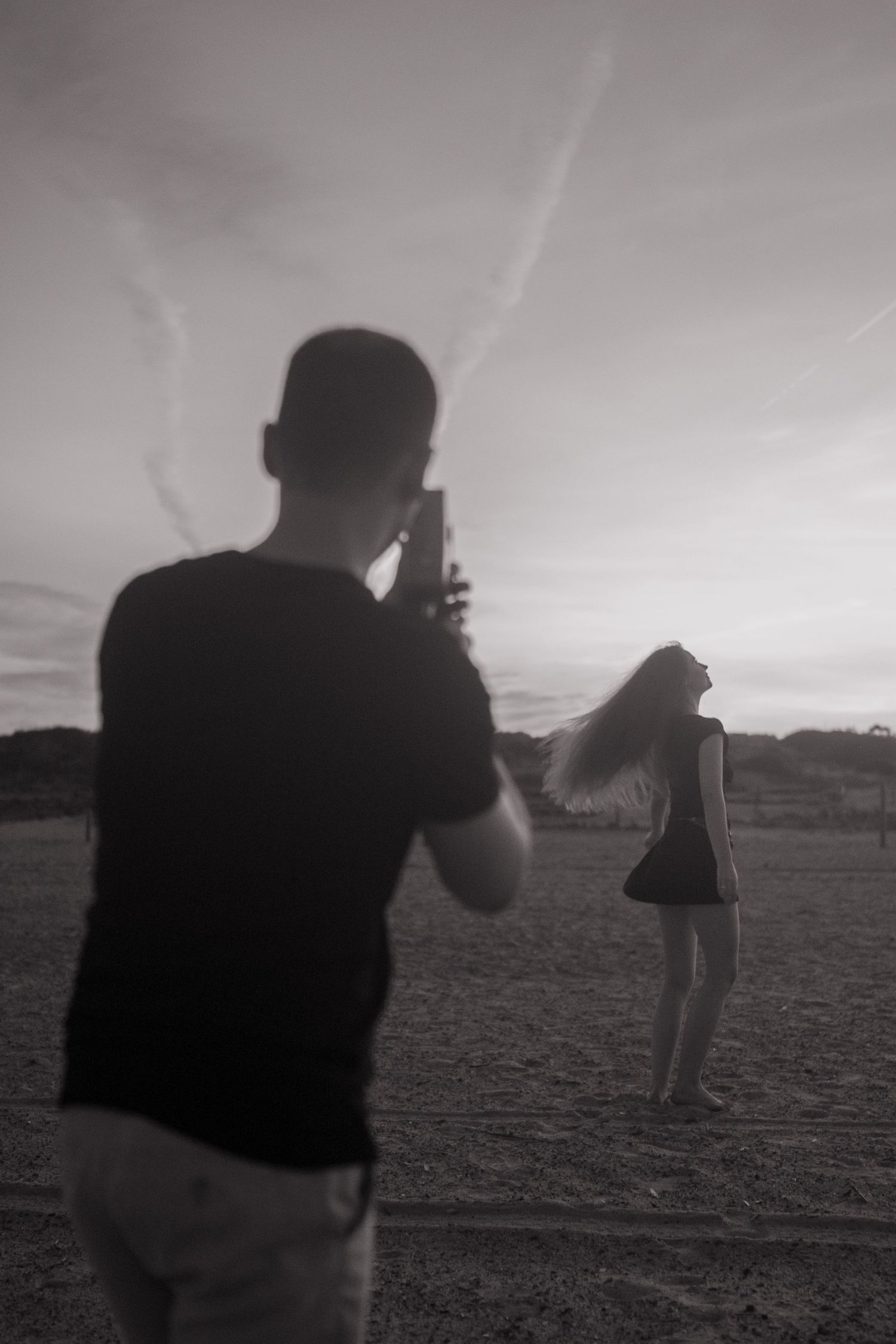 Dramatic silhouettes against a moody sky in a vast open field.