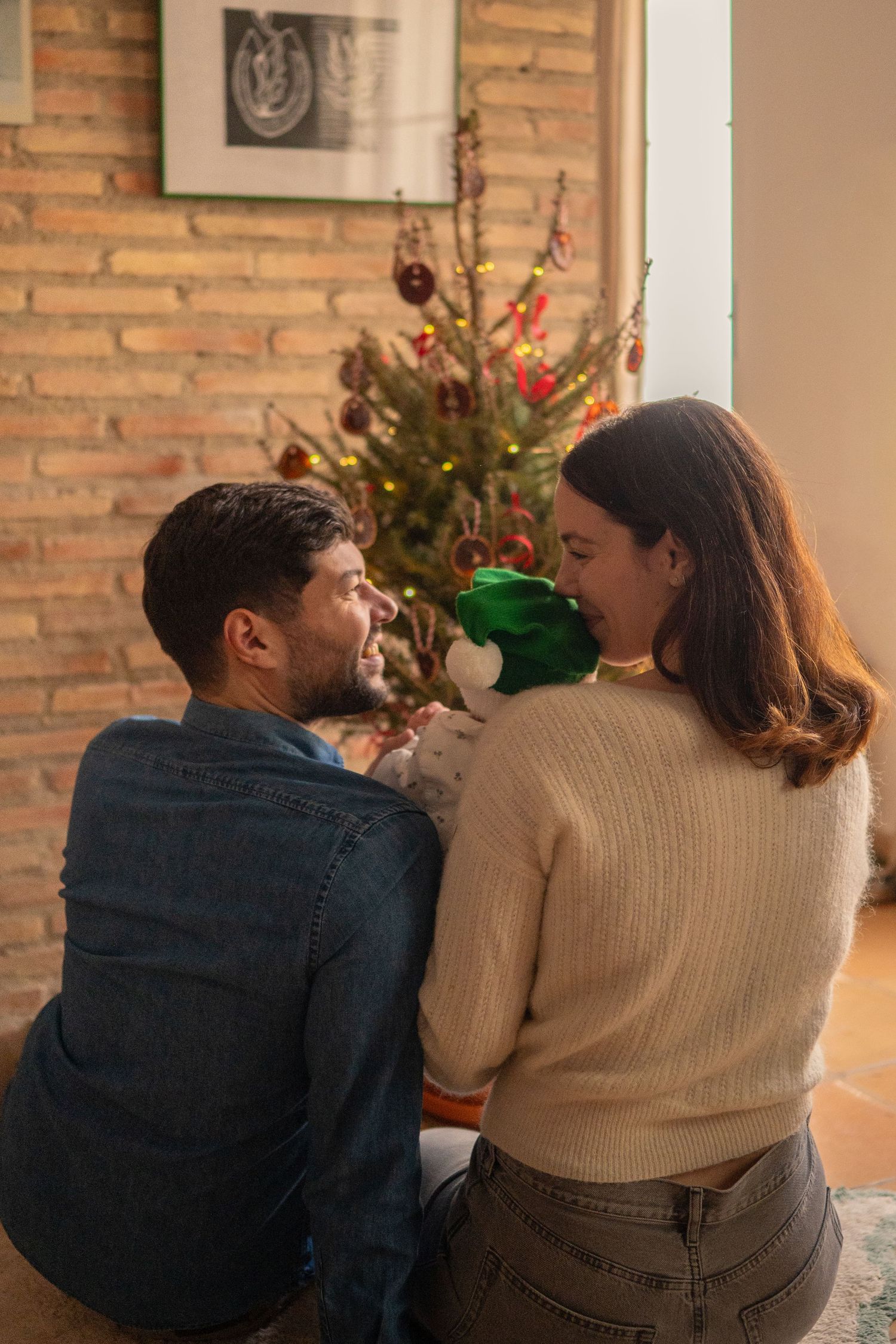 Cozy couple sitting together on sofa near brick wall with natural lighting.