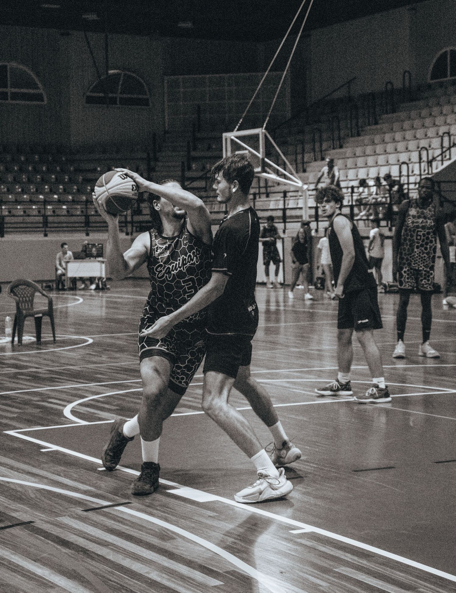 Basketball players practicing defensive drills on a wooden court.
