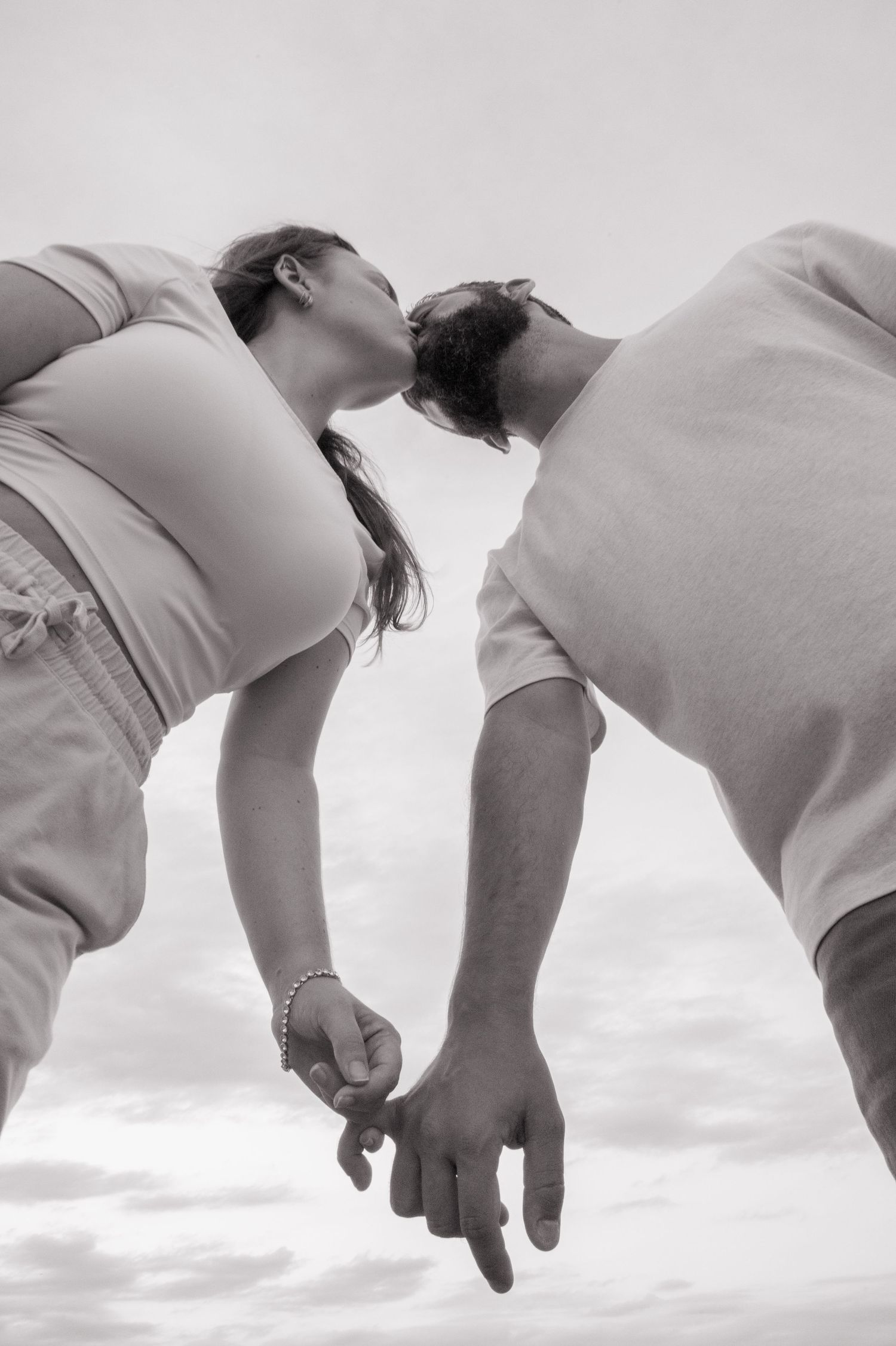 Artistic black and white sequence showing hands reaching downward against a cloudy sky.
