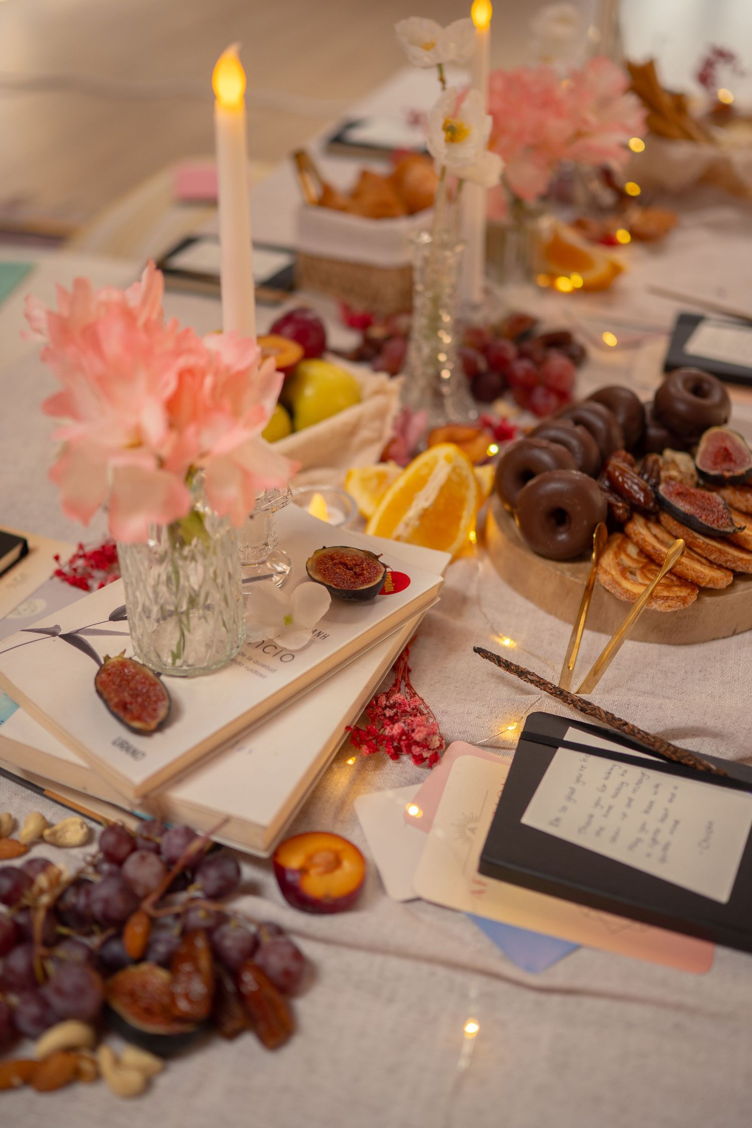Close-up of table decorations featuring candles, fruits, and handwritten notes in warm lighting.