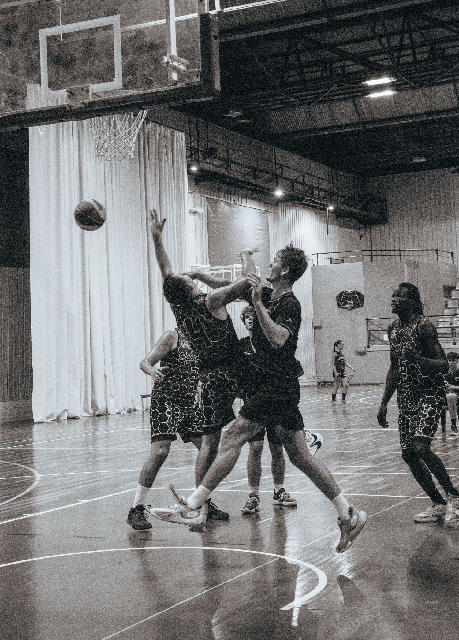 Players executing dynamic basketball moves during an indoor practice session.