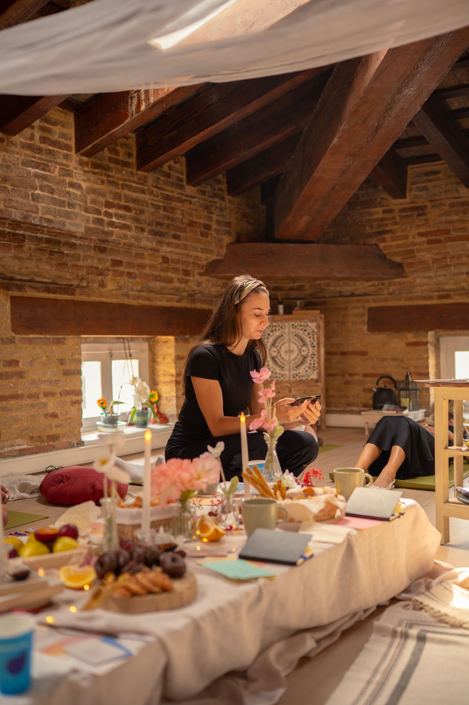 A rustic dining setup in a brick-walled room with exposed wooden beams and a decorated table.