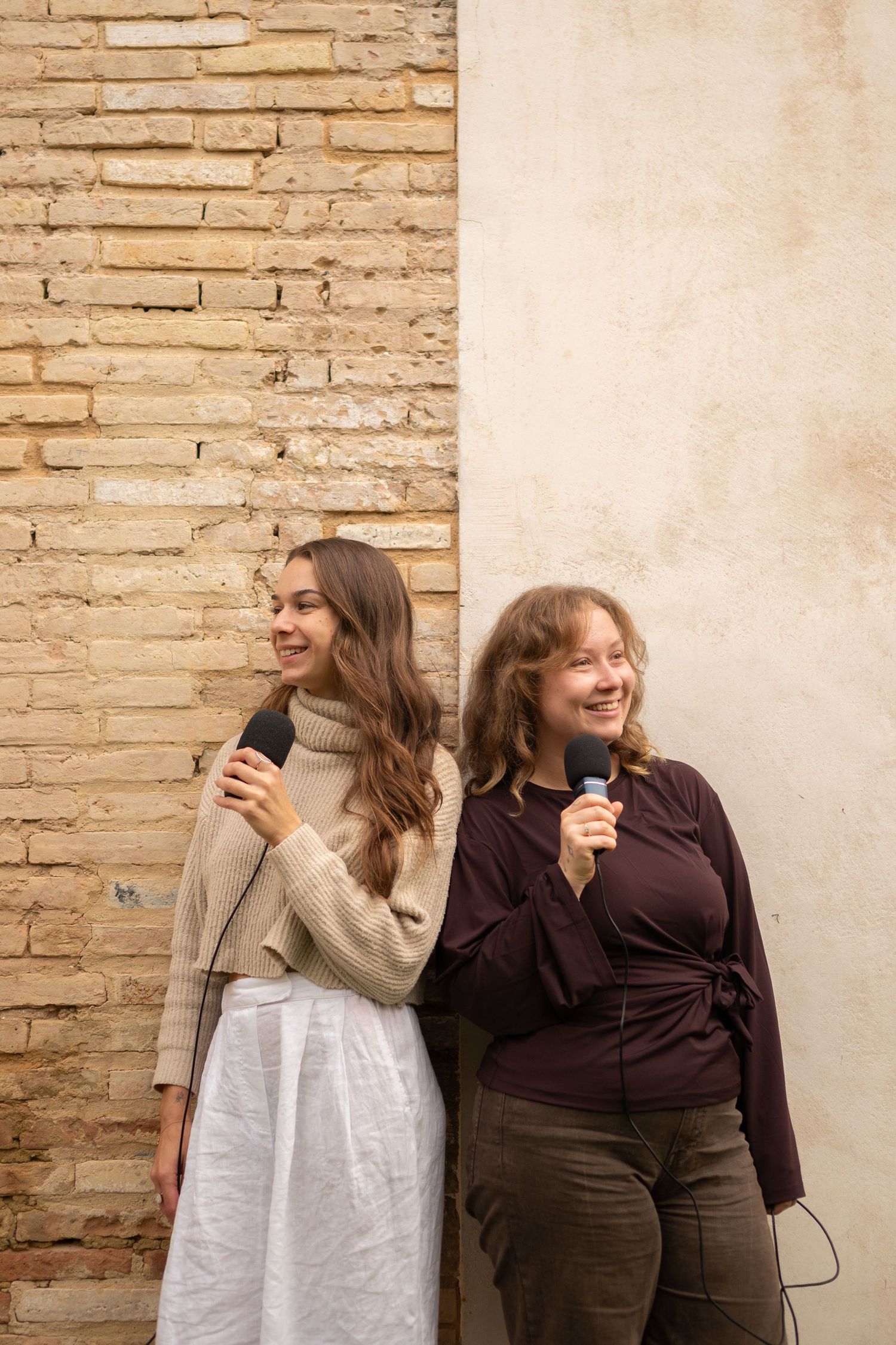 Friends in casual outfits sharing joyful moments against stone wall.