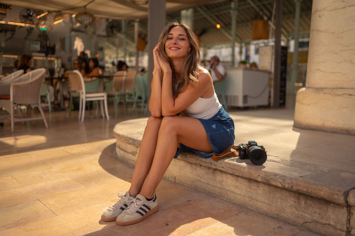 A casual portrait in a sunlit indoor venue with architectural columns and natural lighting.