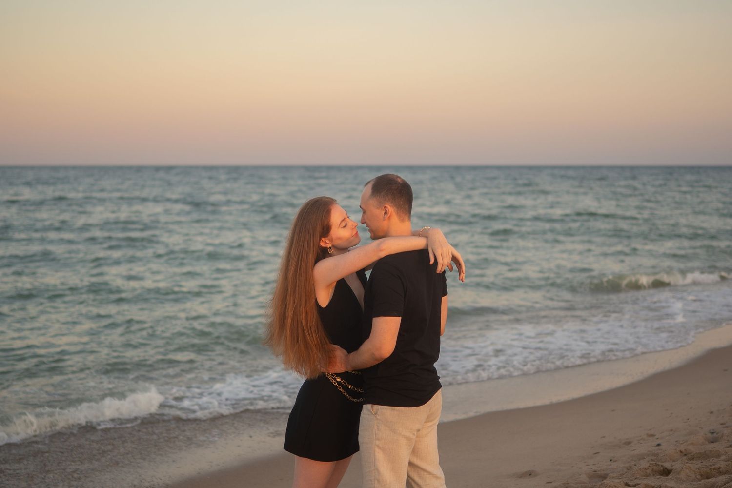 Romantic beach scene with waves crashing on shore during golden hour.