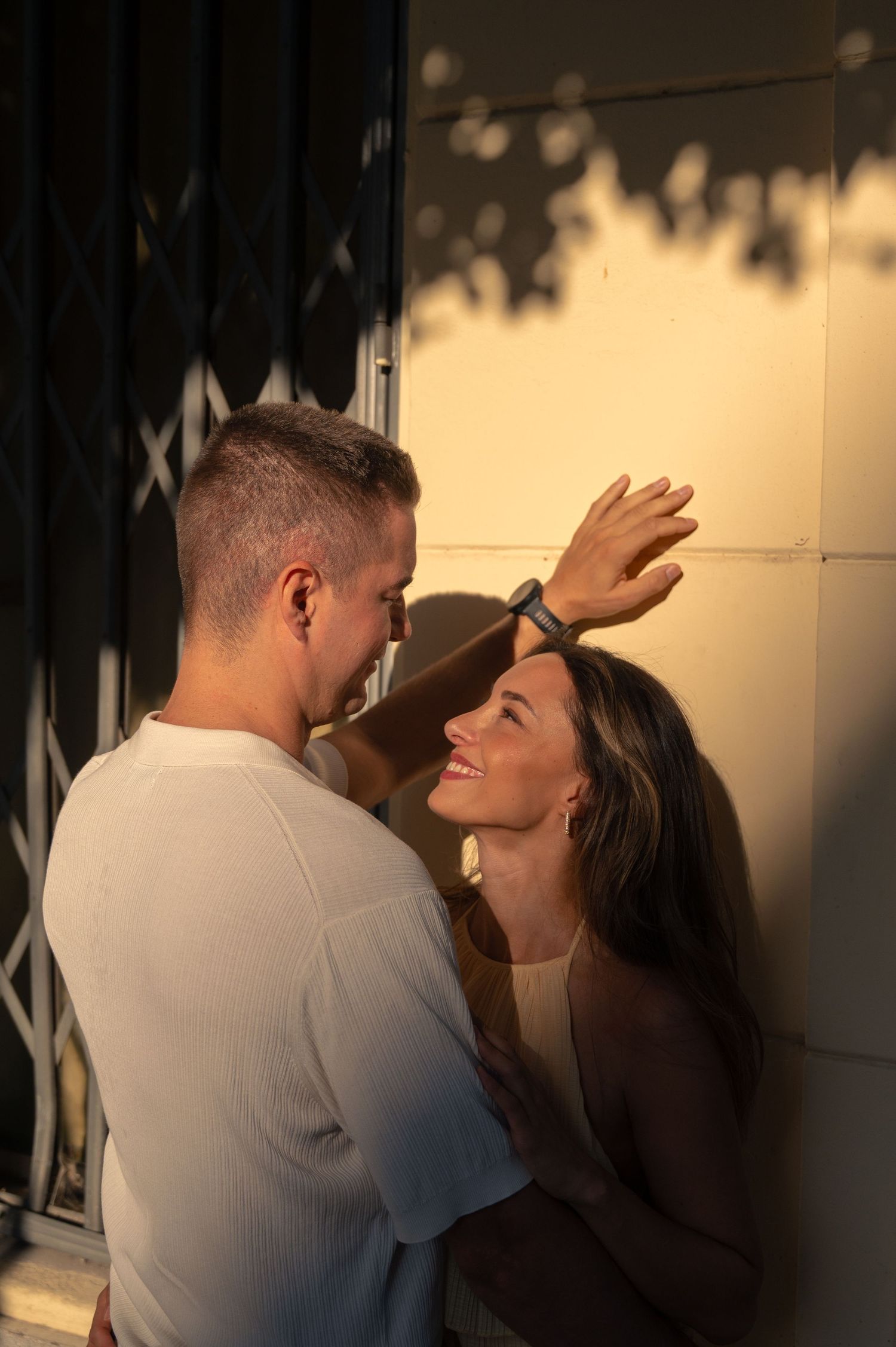 Intimate sequence of a couple in warm lighting against a wall.