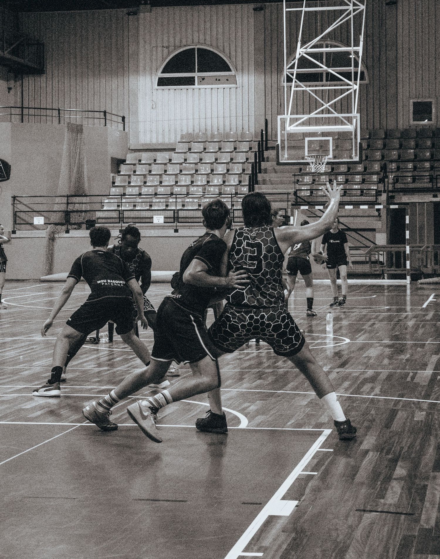 Athletes performing stretching exercises in a gymnasium with wooden floors.