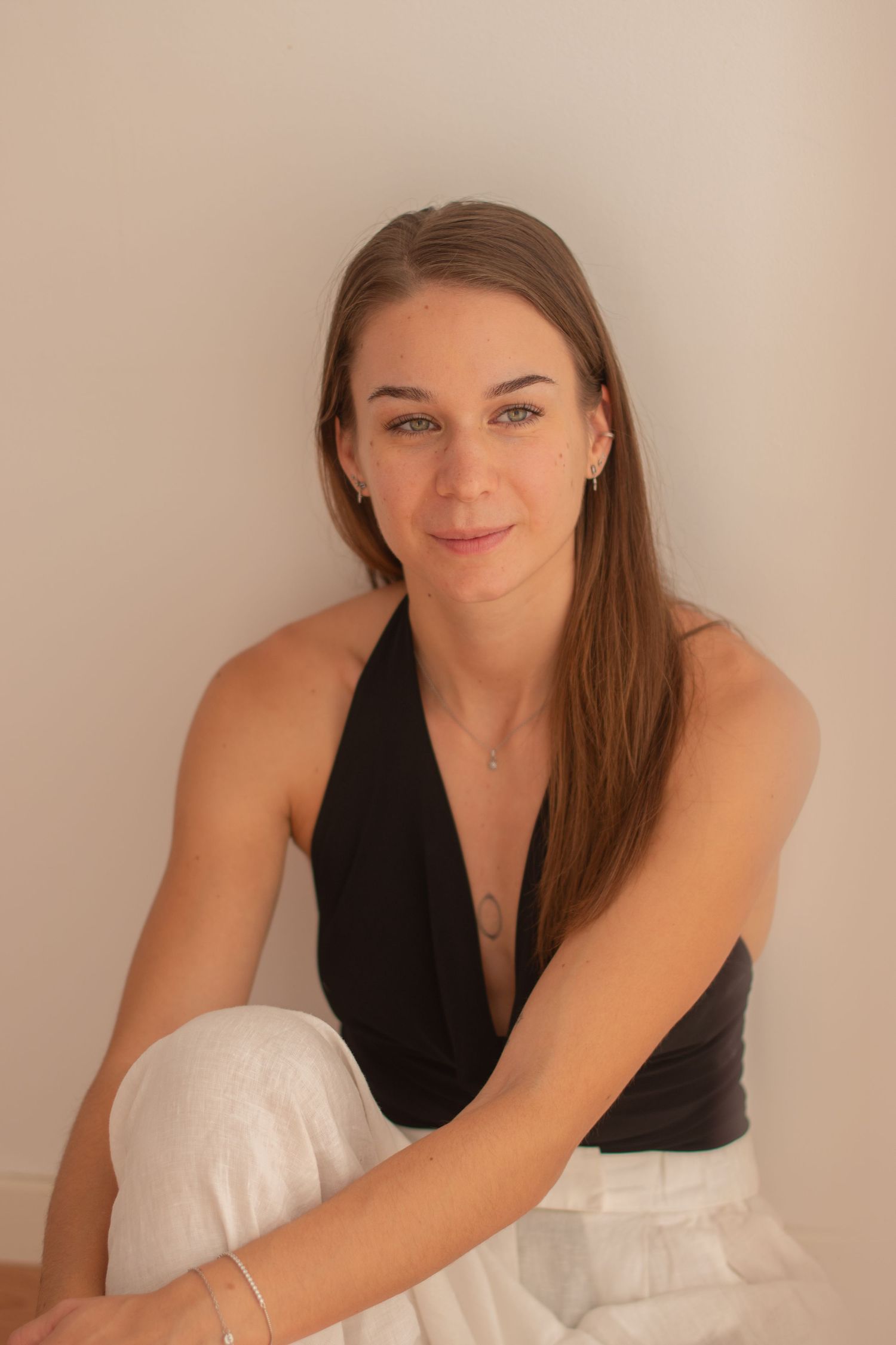 Person in black top posing playfully on white furniture.