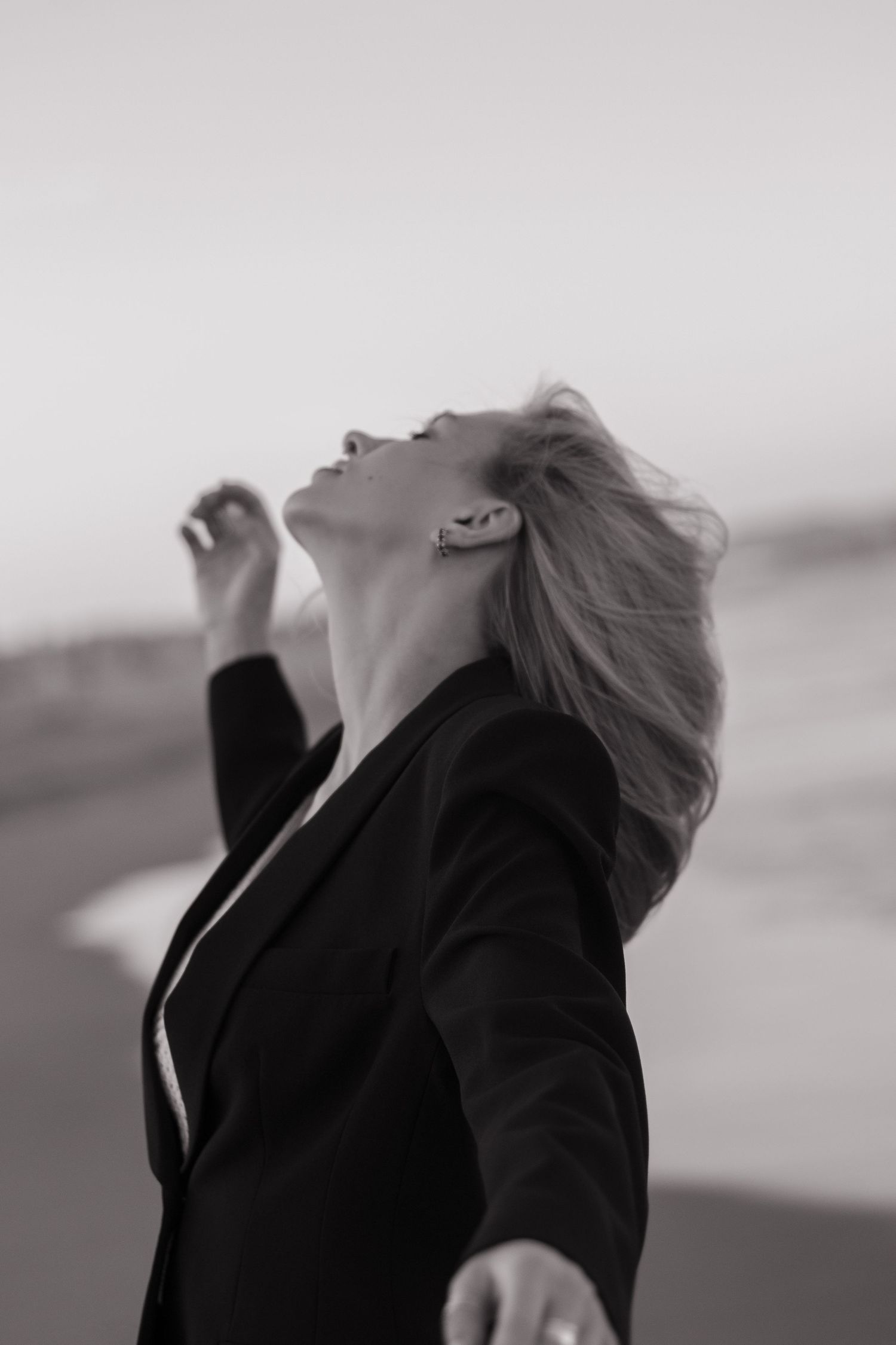 A silhouette poses expressively against an overcast beach backdrop.