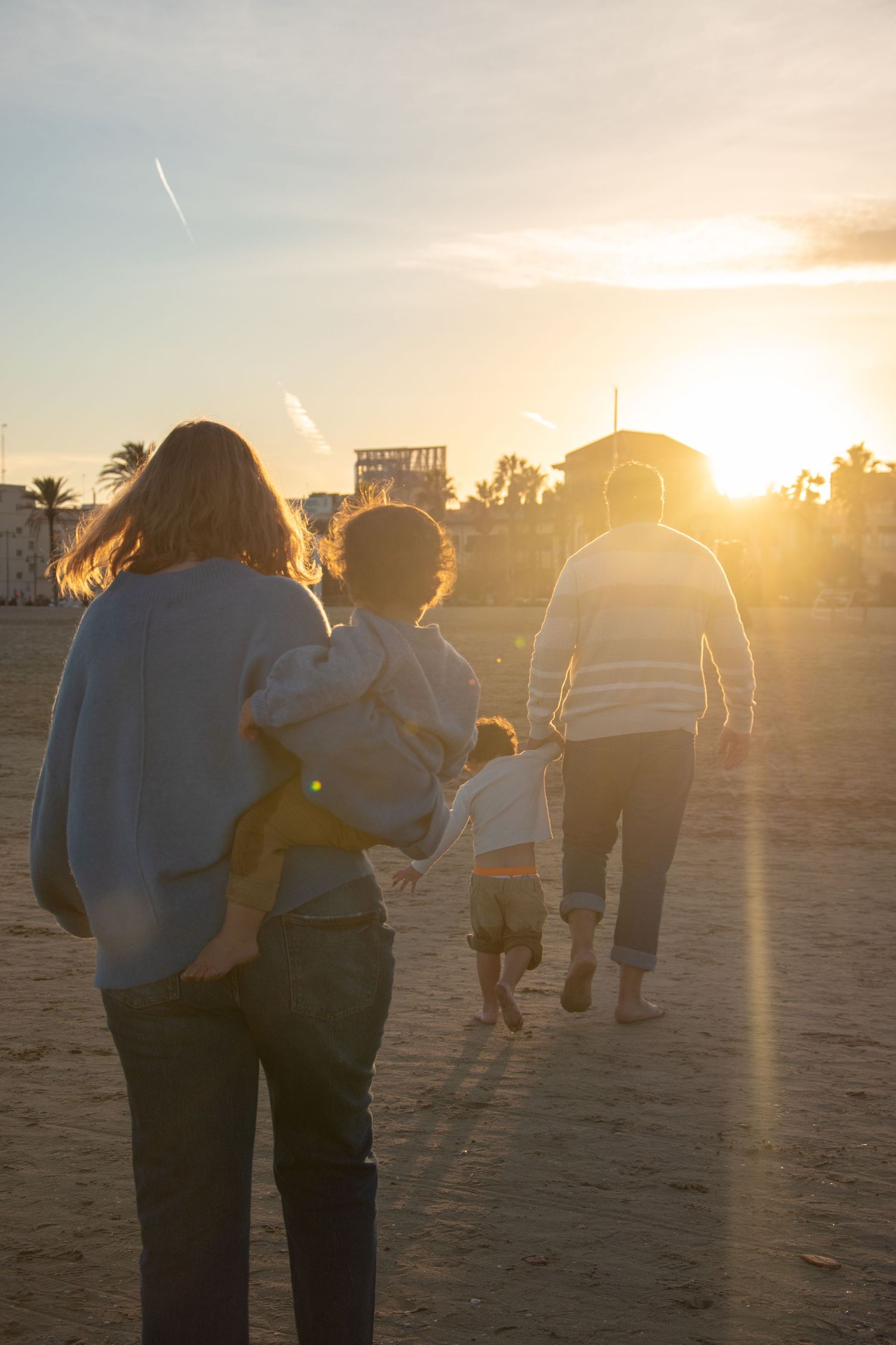 Group walks together on beach silhouetted against dramatic golden sunset.