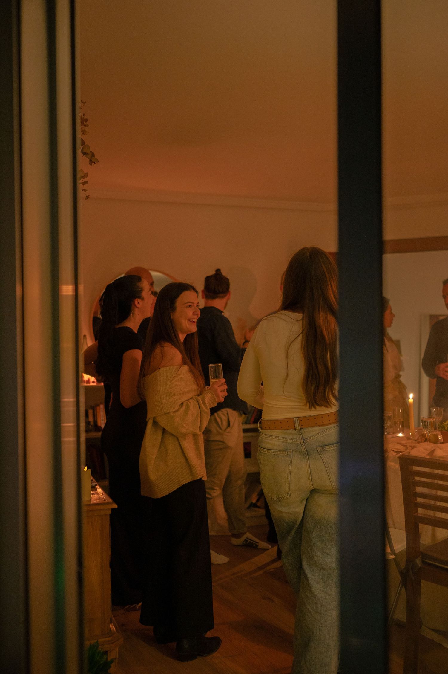 Guests mingling at an evening social gathering in warm ambient lighting.