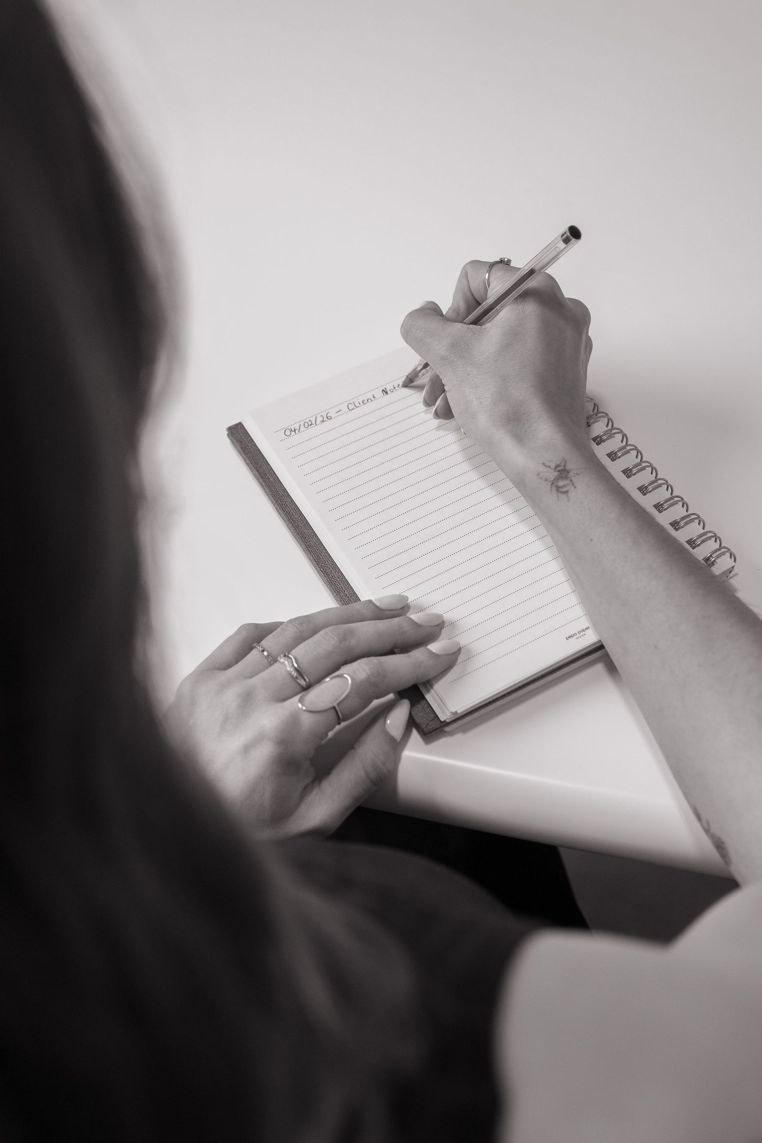 Close-up of hands writing in notebook against white background.