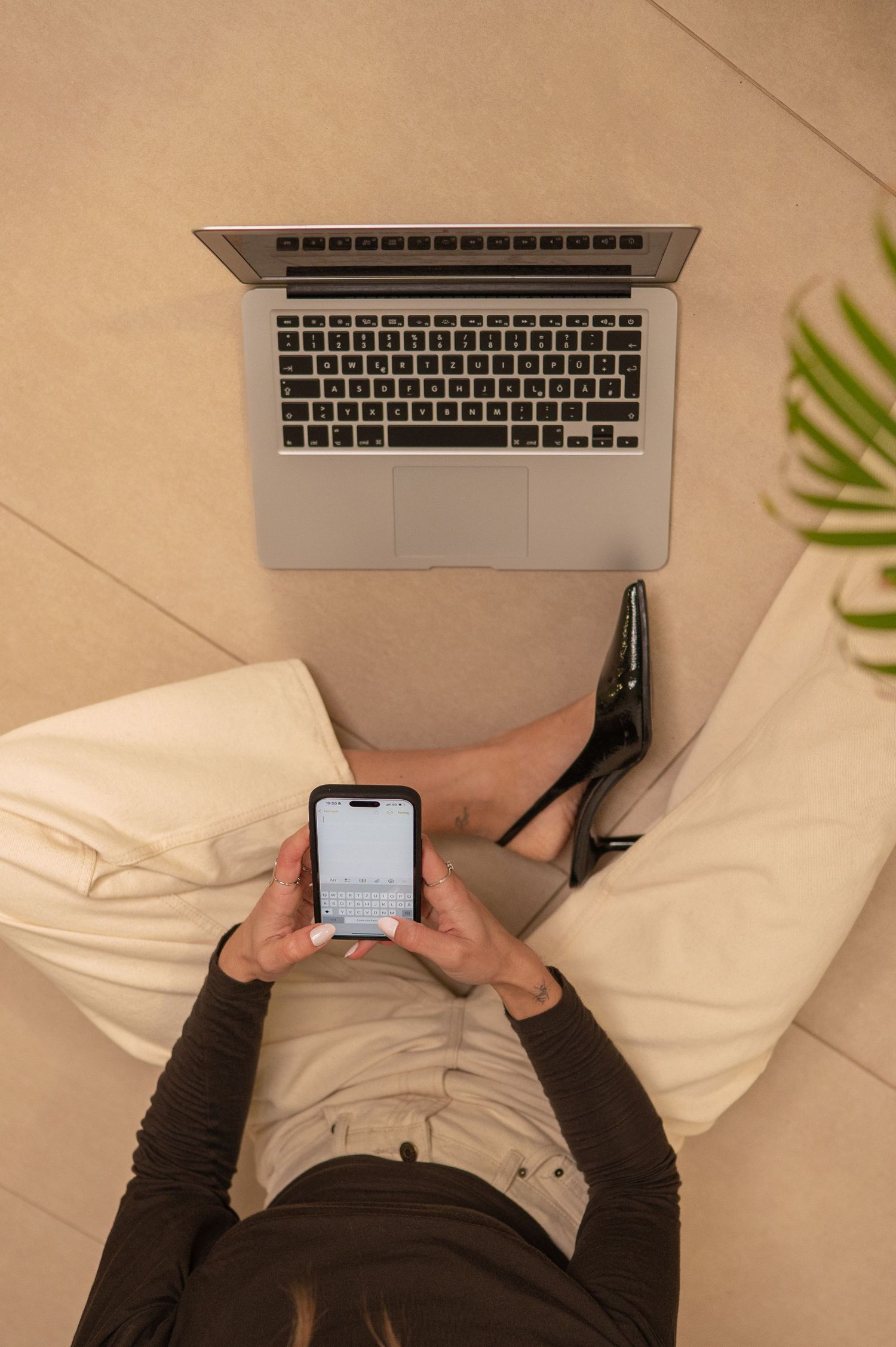 Person lying on floor using laptop and smartphone showing modern digital multitasking behavior.