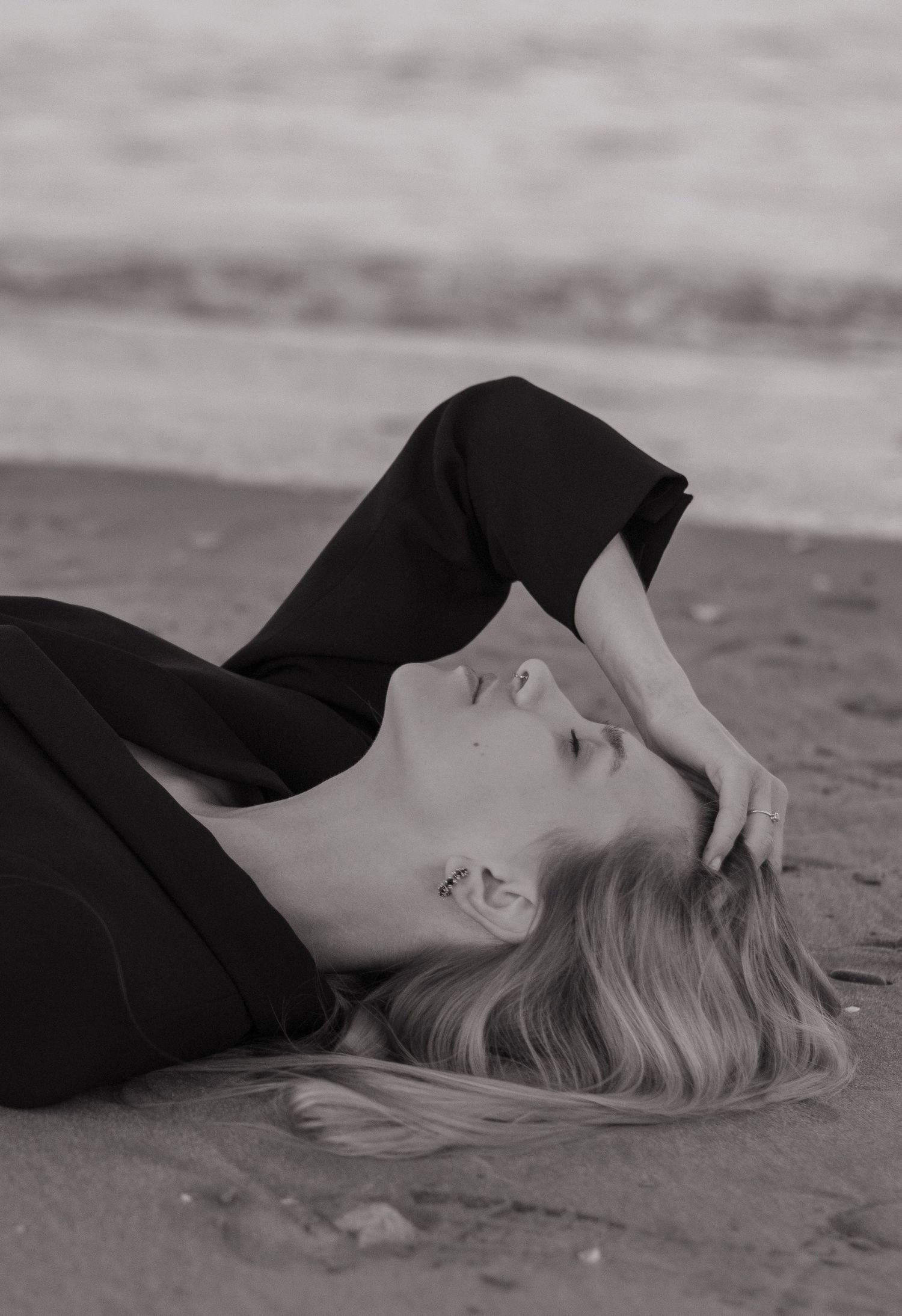 Black and white portrait of woman lying on ground in dramatic poses.