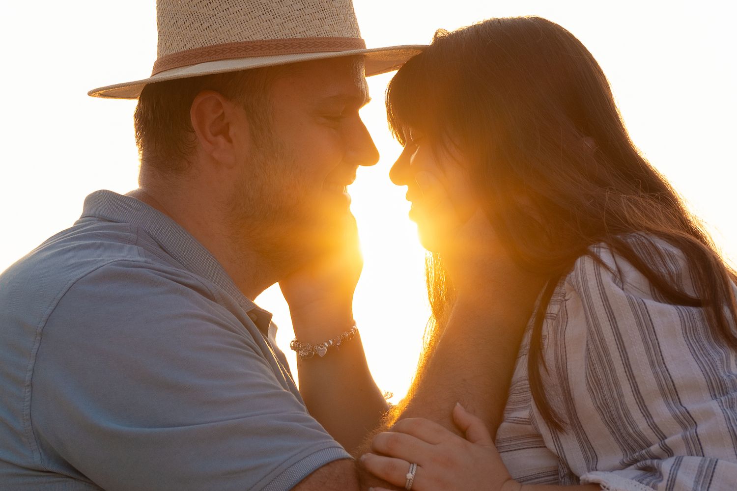 Romantic silhouettes against an orange sunset sky at the beach.