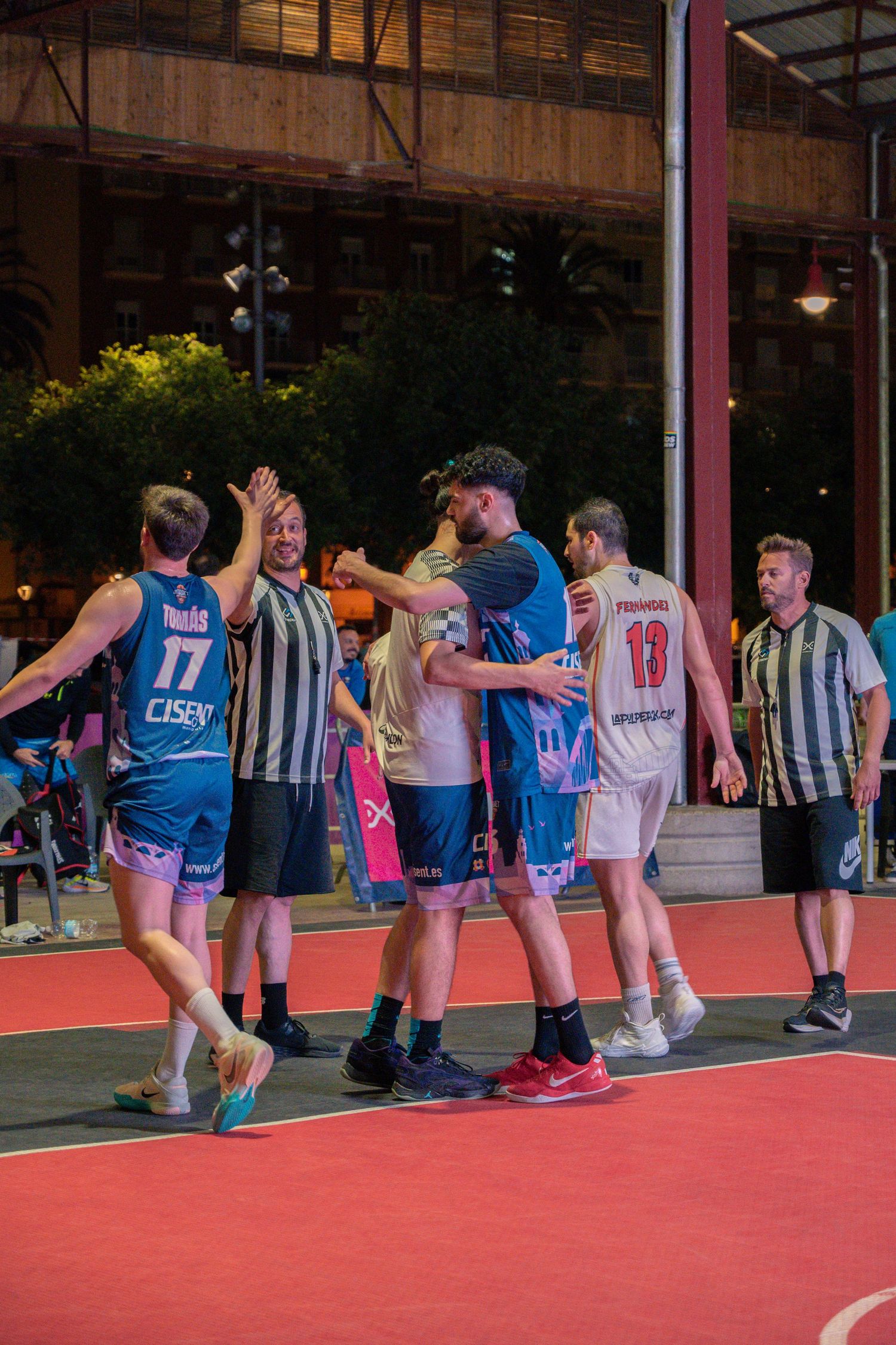 Players lined up on a red court surface during a basketball training session.