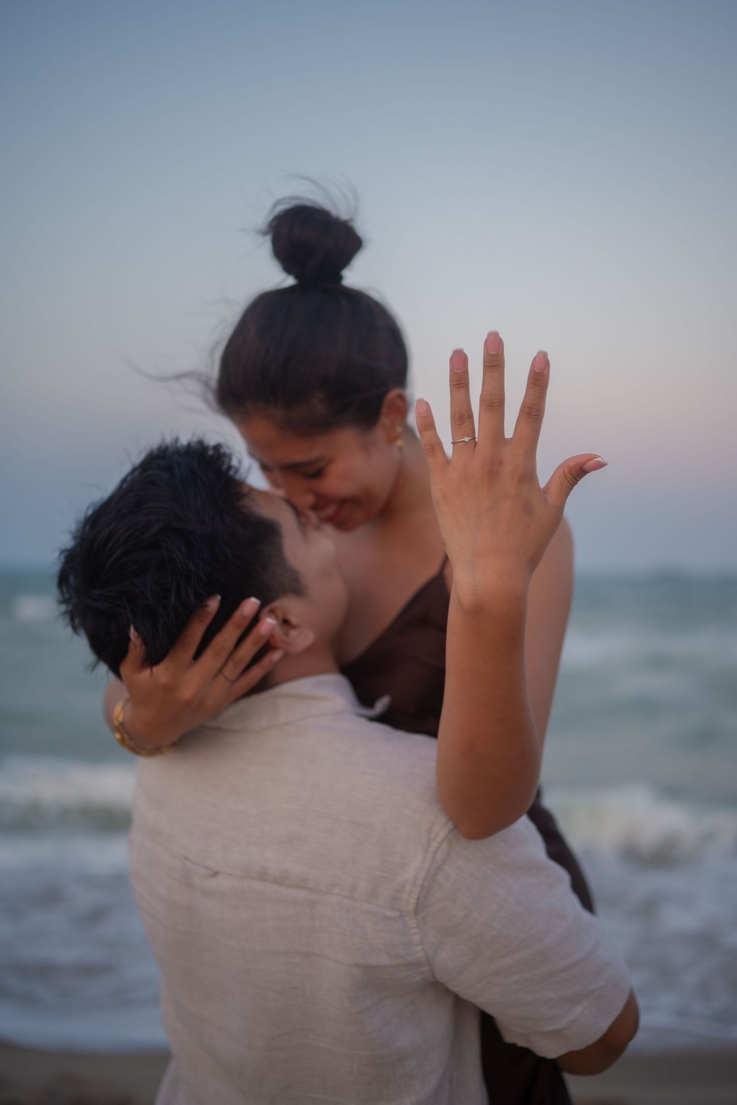 A couple embracing on a beach during golden hour.
