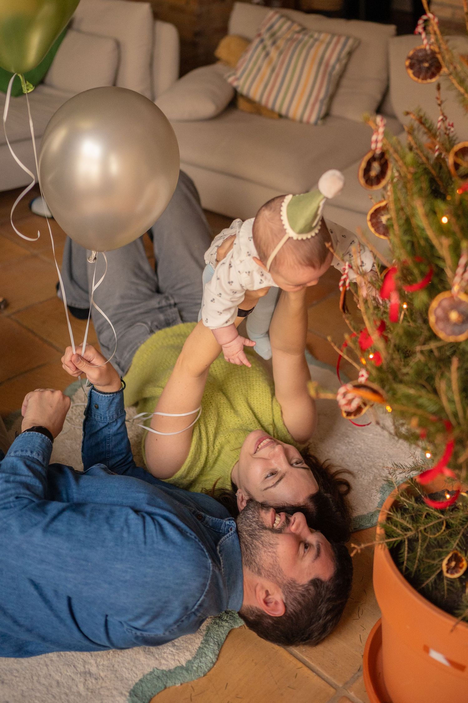 Family enjoying playful moments near a decorated Christmas tree indoors.