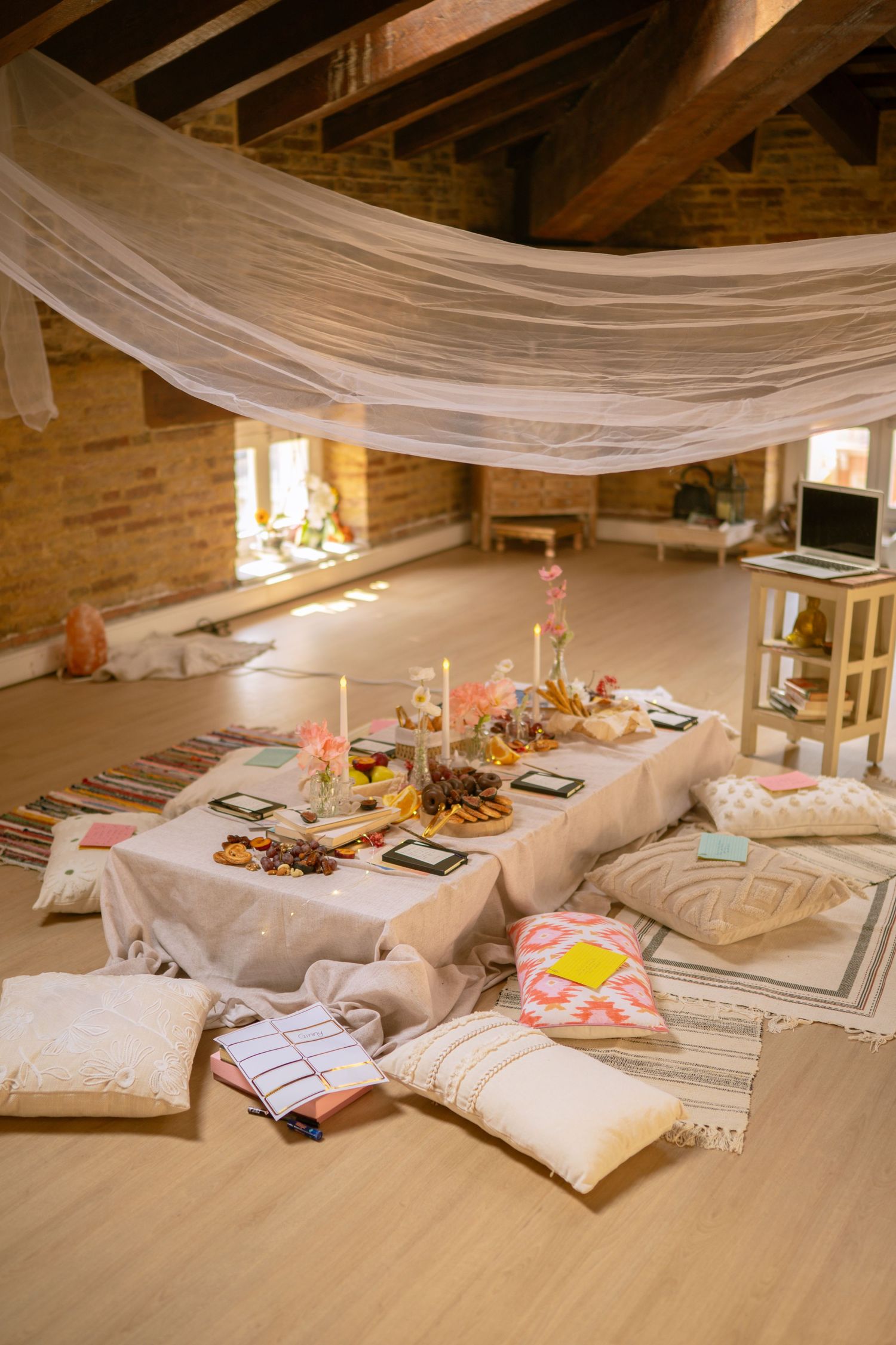 Cozy indoor space with white drapes and cushions arranged for a relaxing gathering.