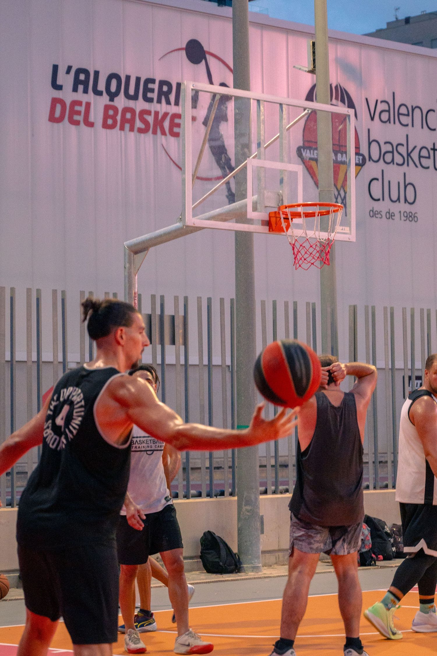 Players practicing basketball at L'Aloueri del Baske Valencia basketball club outdoor court.