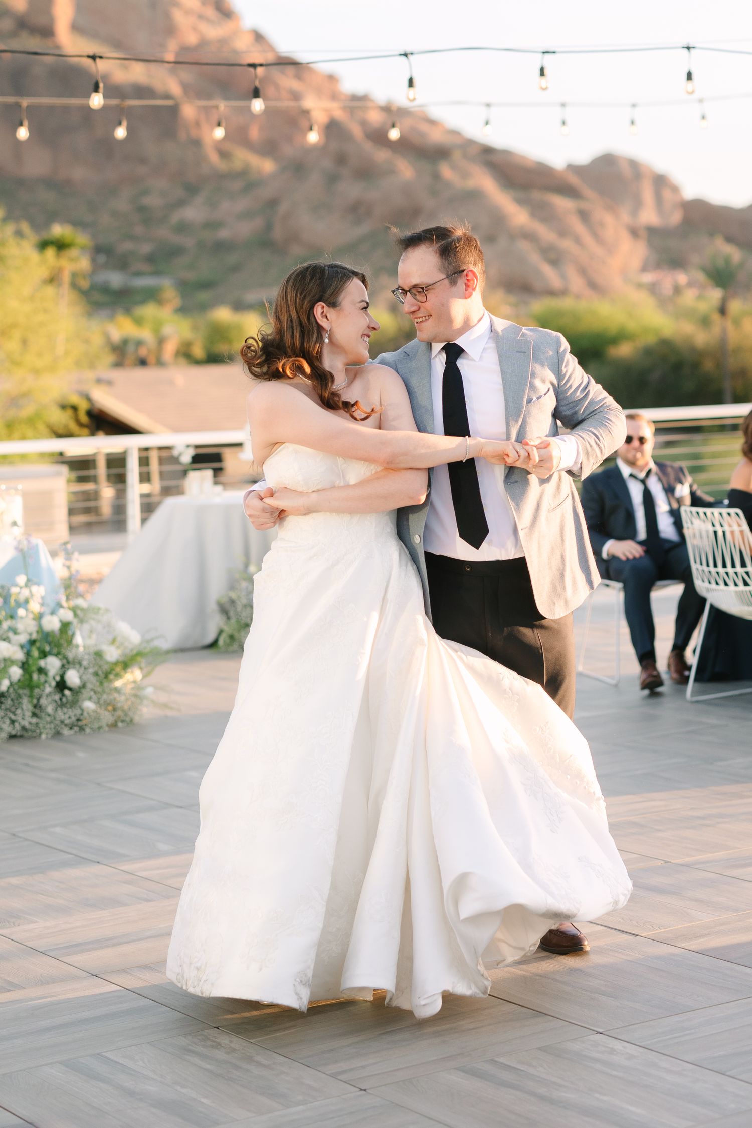 A couple dancing at an outdoor wedding reception with string lights and mountain backdrop. Molly McPhoto