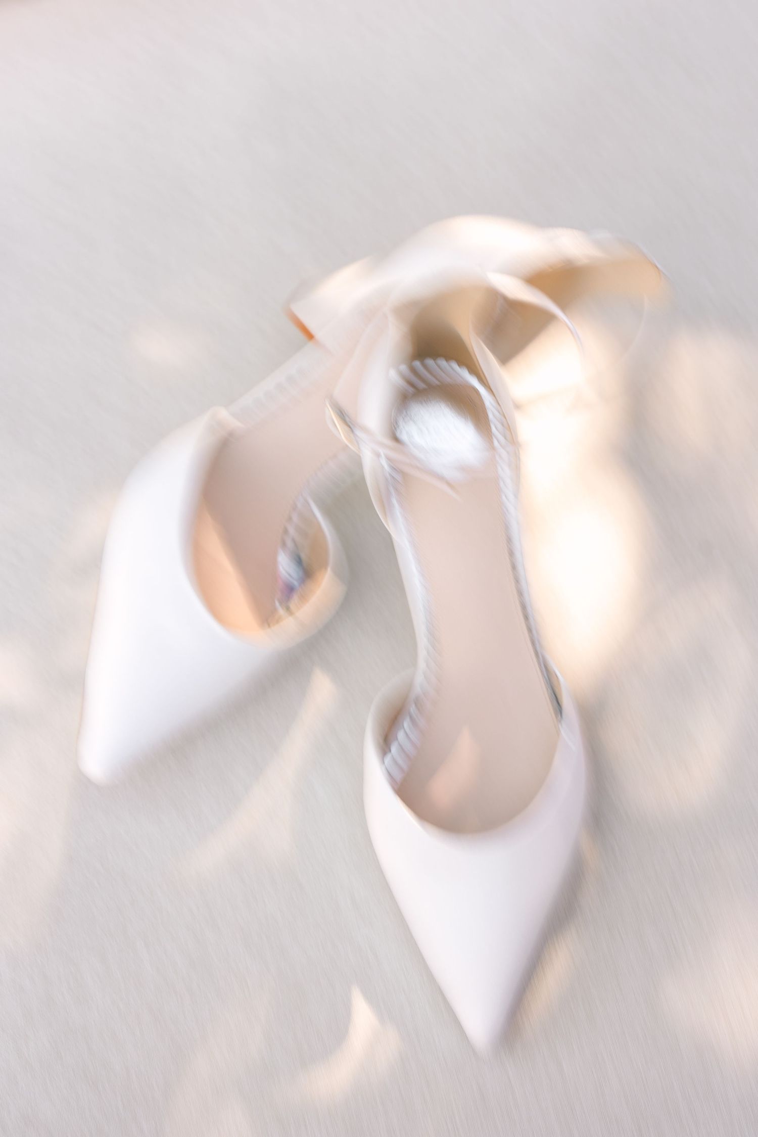 Close-up shot of elegant white bridal shoes in soft lighting.
