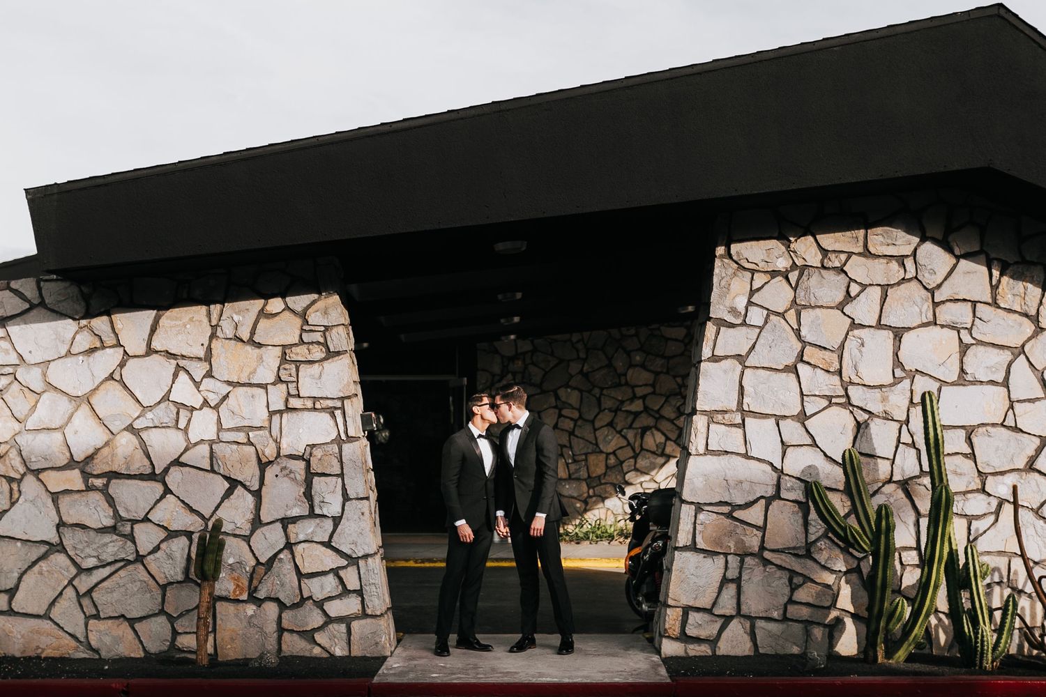 Modern stone wall wedding venue exterior with dramatic silhouettes.
