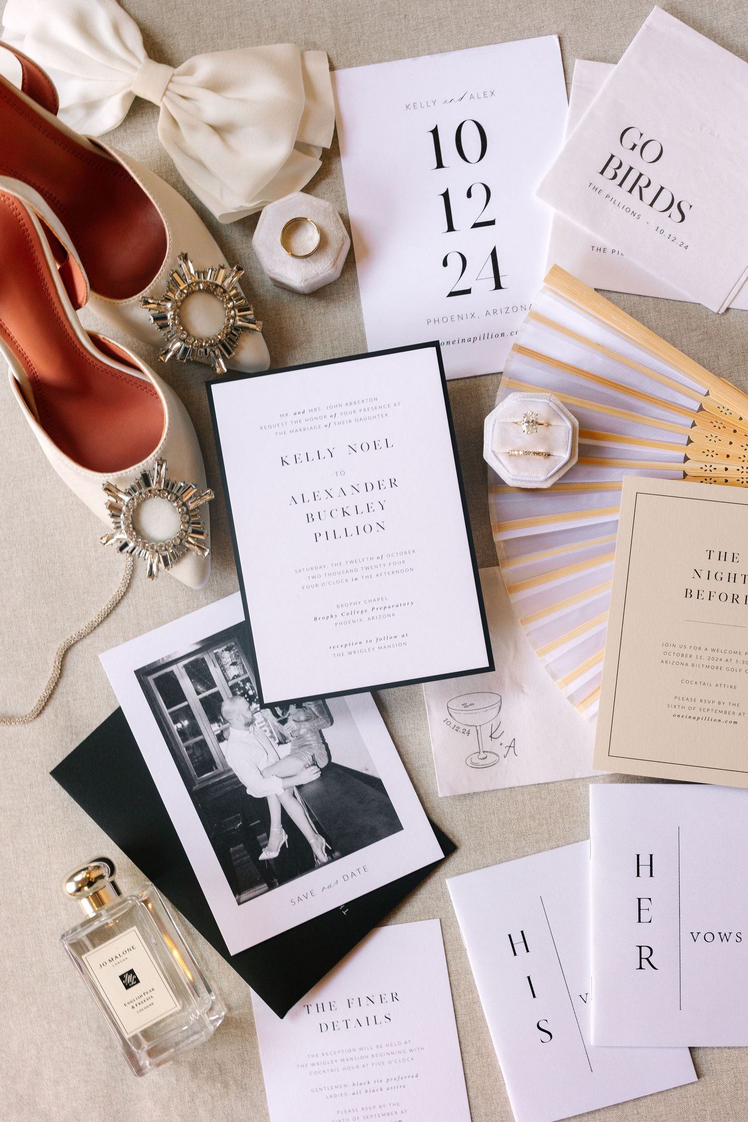 Wedding stationery flat lay with invitations, perfume, and vintage photographs on beige linen.