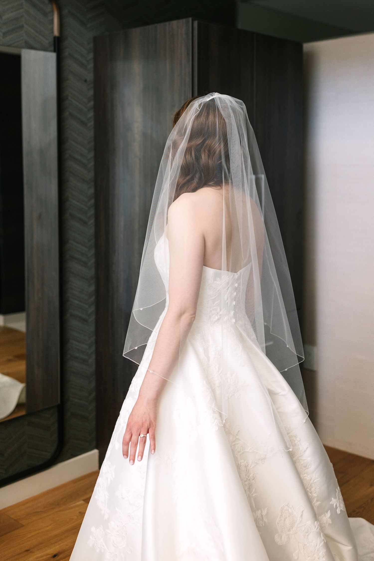 Back view of a bride in a classic white wedding gown with sheer veil. Molly McPhoto
