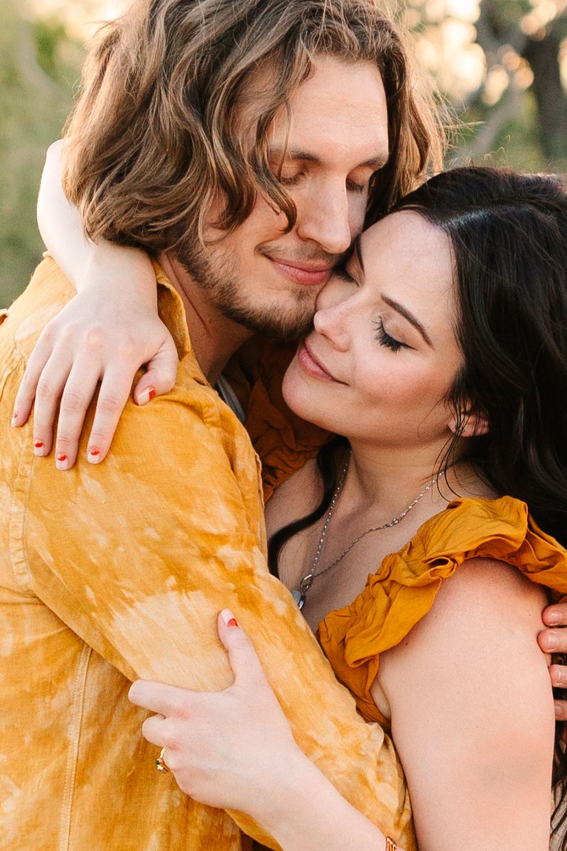 A couple sharing intimate moments in a tender embrace while one wears a golden yellow jacket.