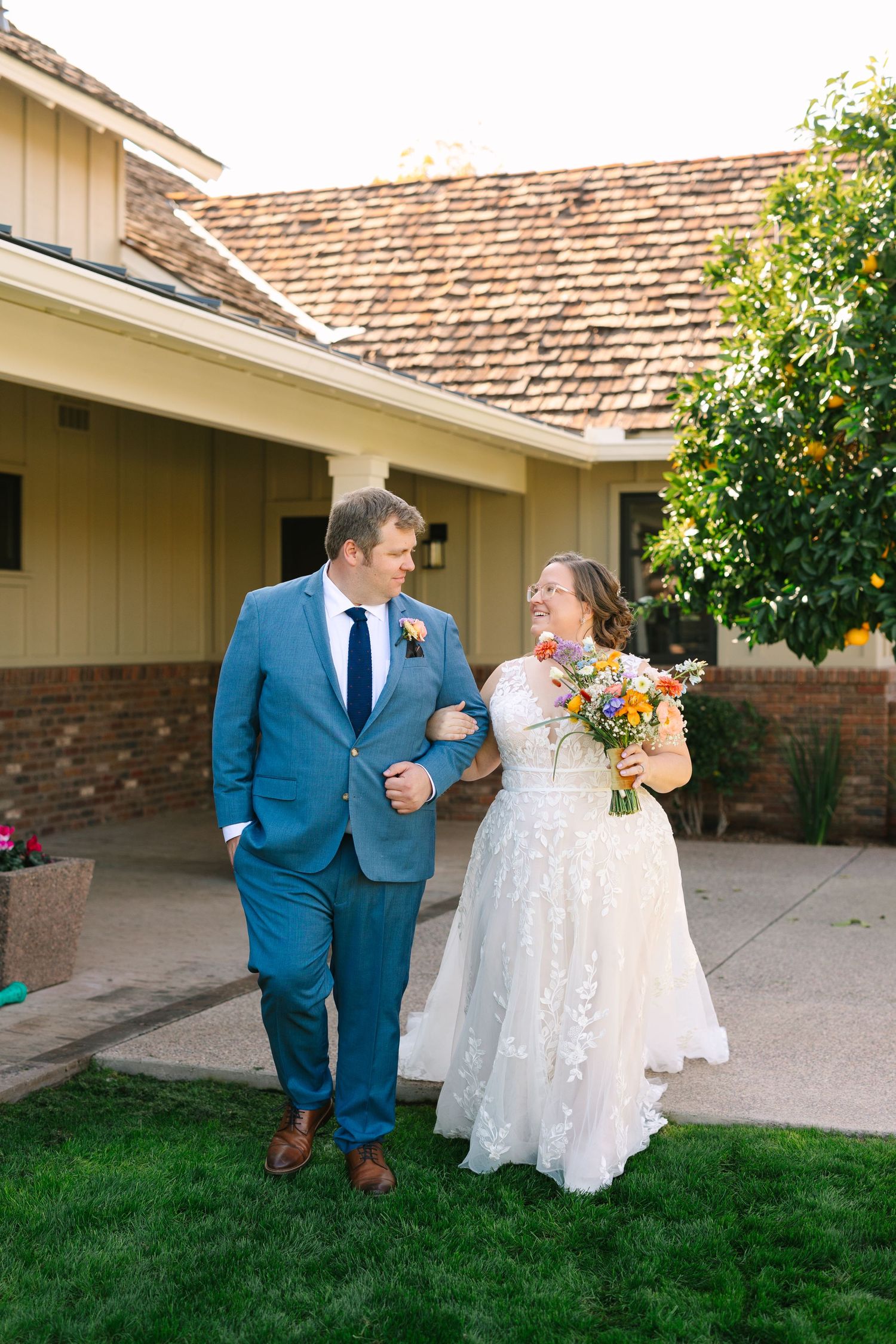 A cheerful couple walking together outside a ranch-style home. Molly McPhoto