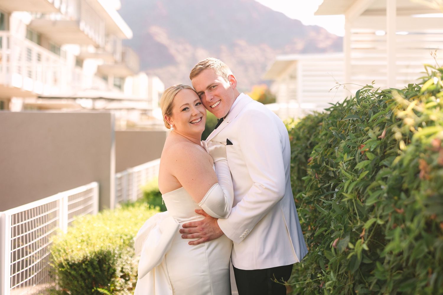 Wedding couple shares intimate moments in a garden setting during sunset.