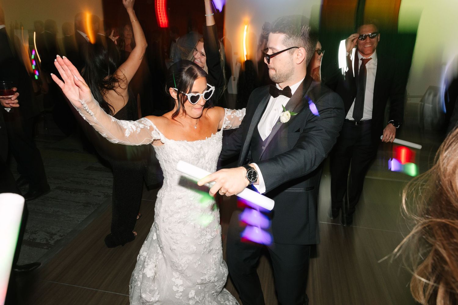 Dancing celebration at wedding reception with colorful party lighting.