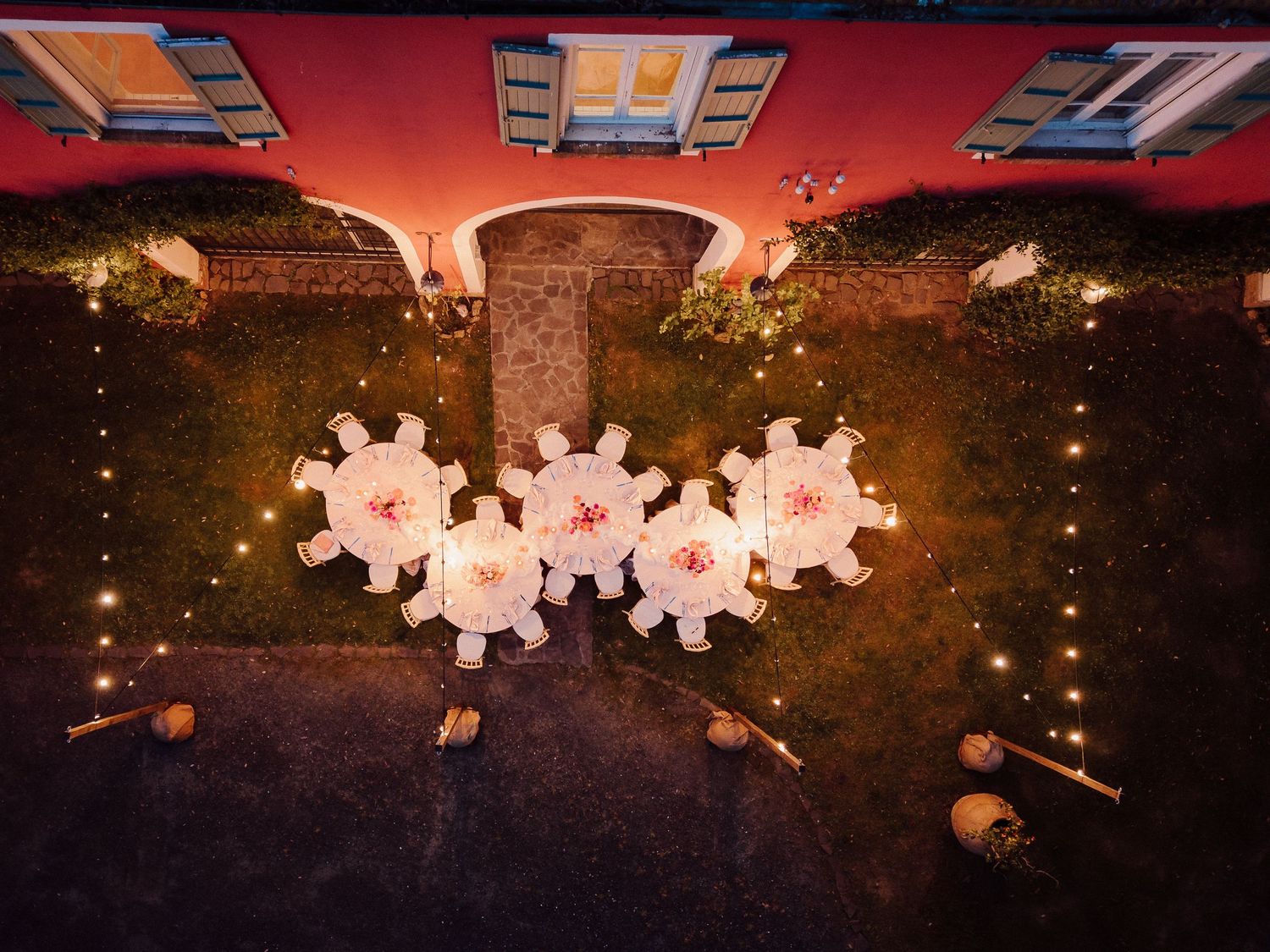 Overhead view of outdoor wedding reception with illuminated snowflake decorations at dusk.