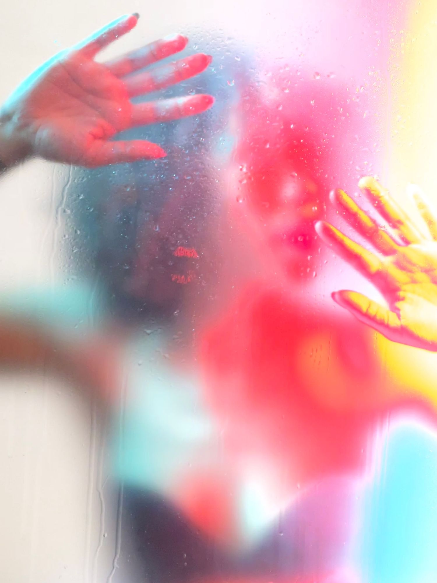Abstract artistic photograph of hands against colorful red and blue light effects.