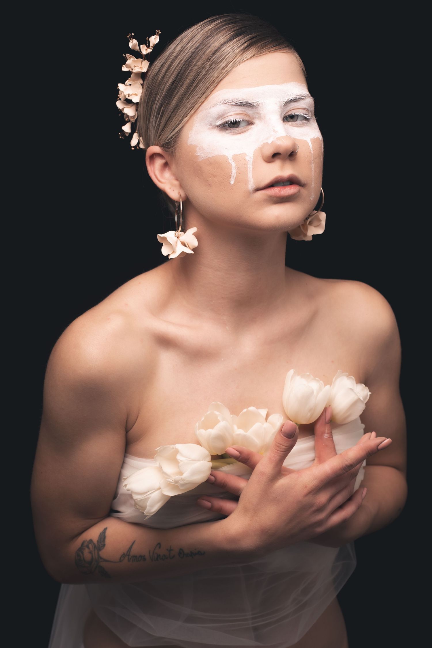 Artistic nude portrait with white face paint and peach-colored flowers.