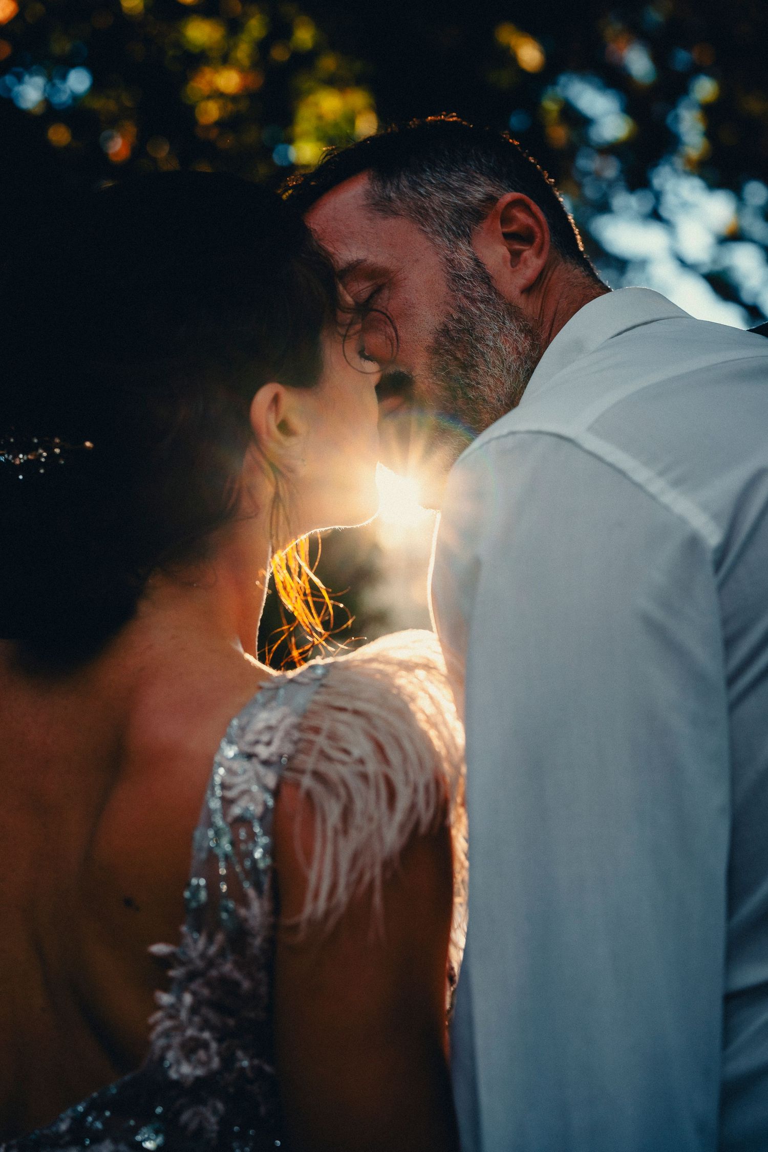 A backlit sunset wedding portrait capturing an intimate moment with golden light.