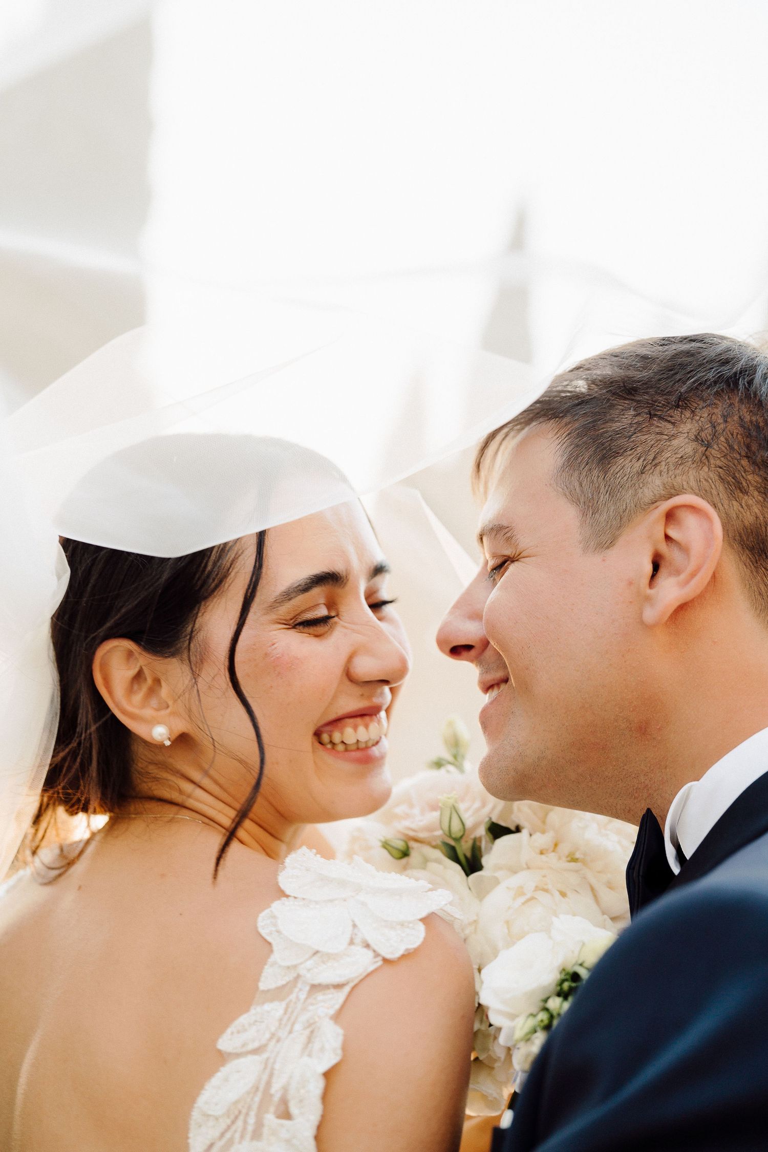 A joyful wedding moment captured between newlyweds with white flowers in the background.