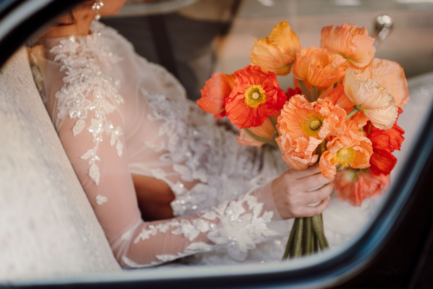 Close-up of coral-colored flowers next to white fabric with delicate details.