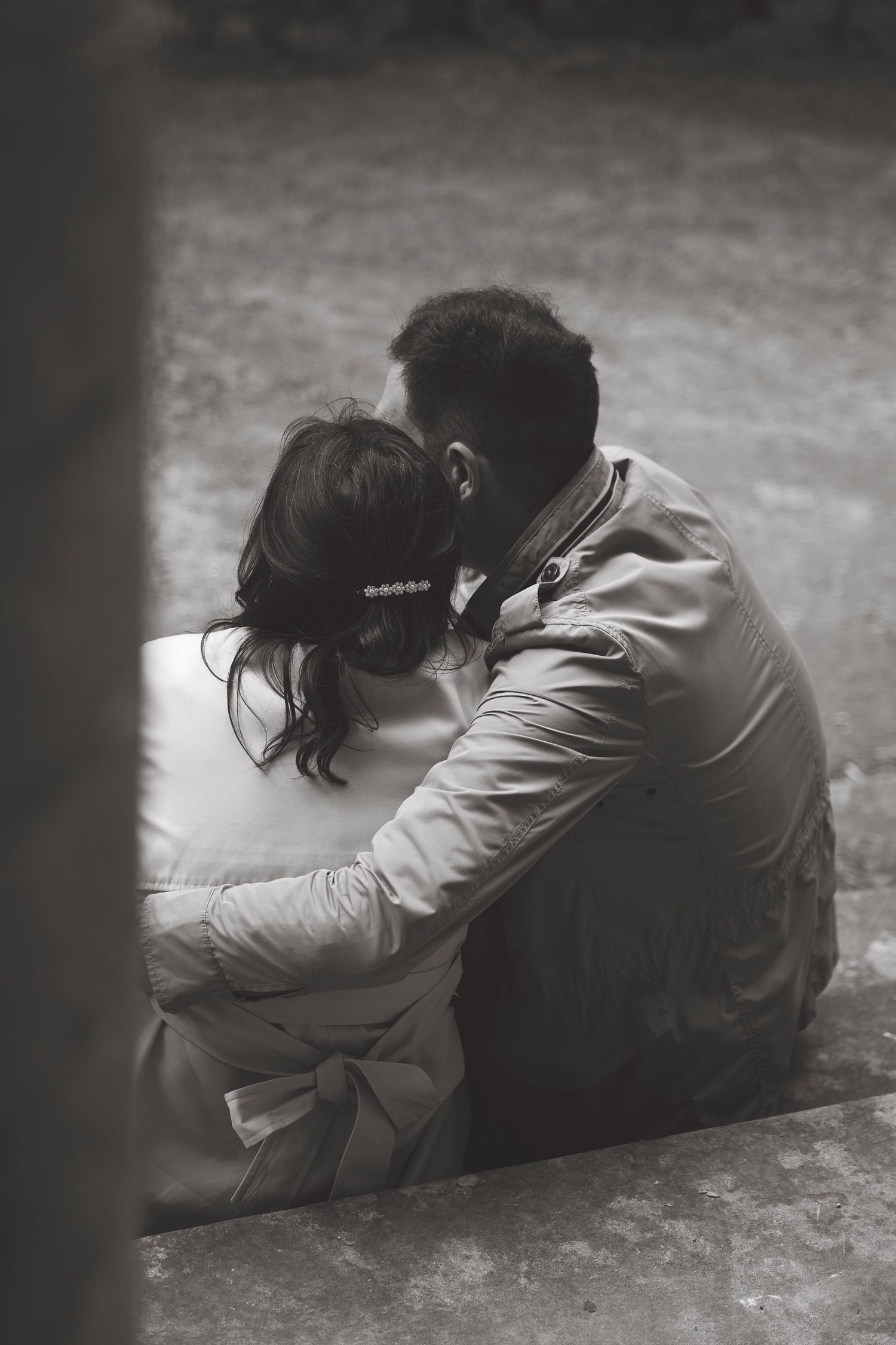 An intimate black and white photo of a couple sharing a quiet moment on steps.