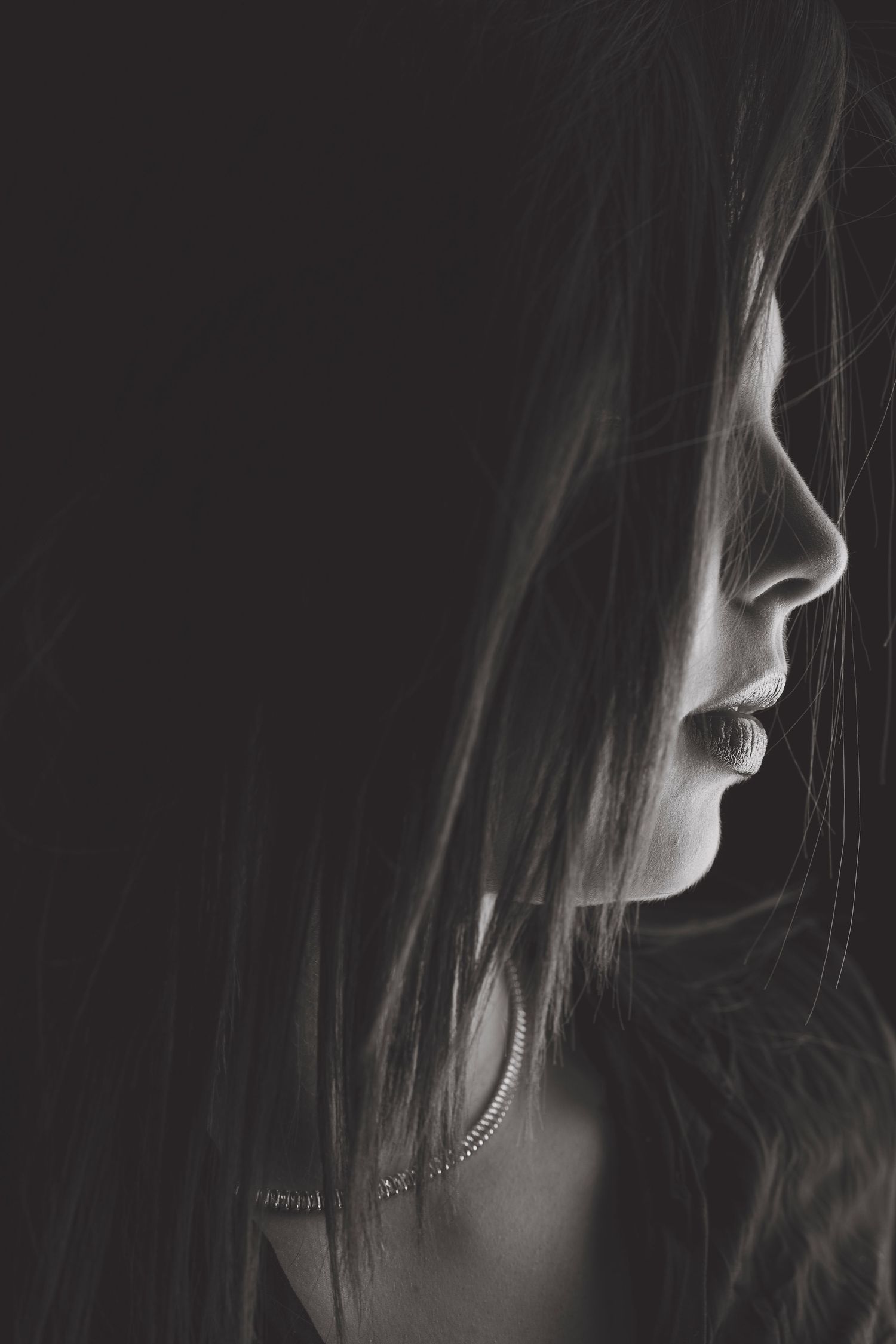 Side profile silhouette captured in black and white with soft lighting highlighting facial features.